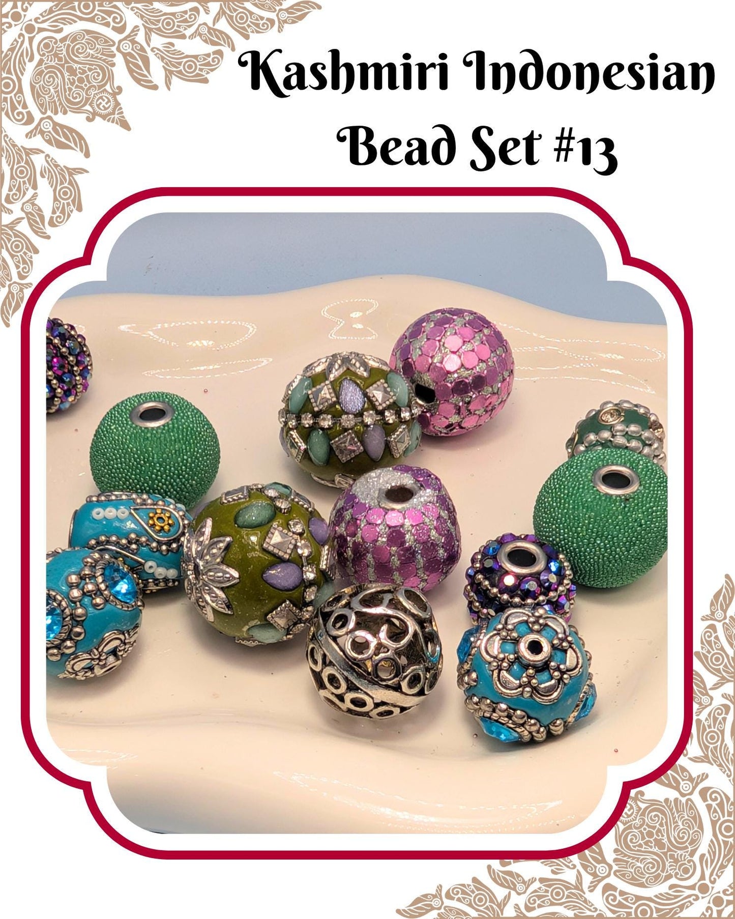 A collection of colorful, intricately designed beads in various shapes and sizes, including green, purple, blue, and silver beads, arranged on a white surface.
