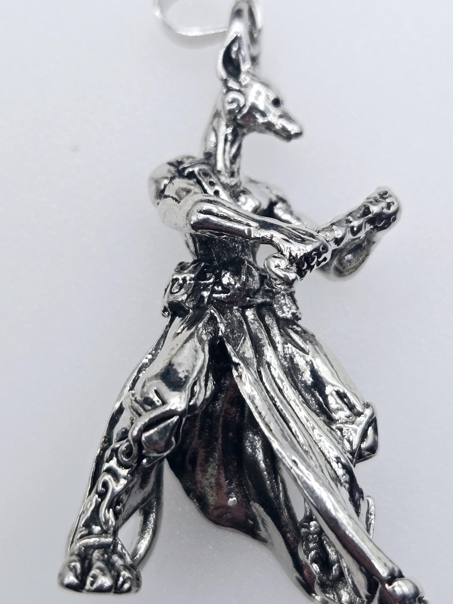 A close-up view of a silver-colored metal charm or pendant, featuring an intricate and detailed design.