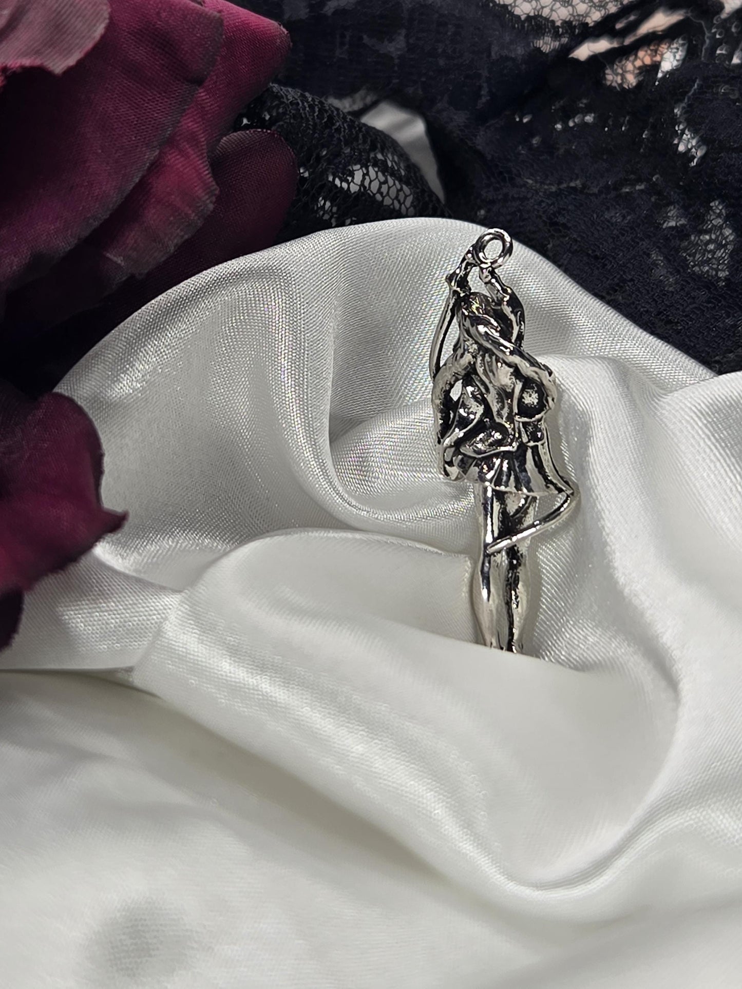 a silver brooch with a unique design, placed on a white fabric surface.