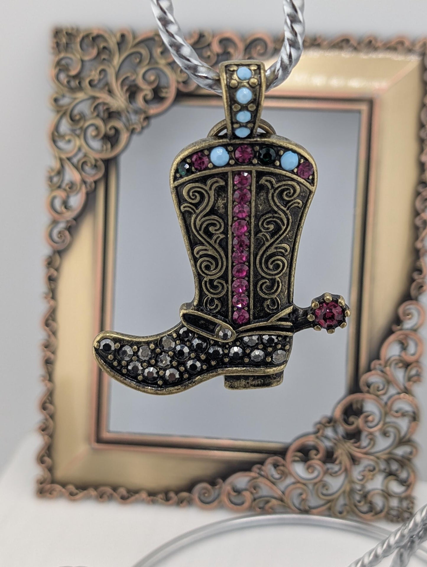 A decorative pendant featuring a detailed, ornate boot with a sparkling crystal accent, hanging from a chain.