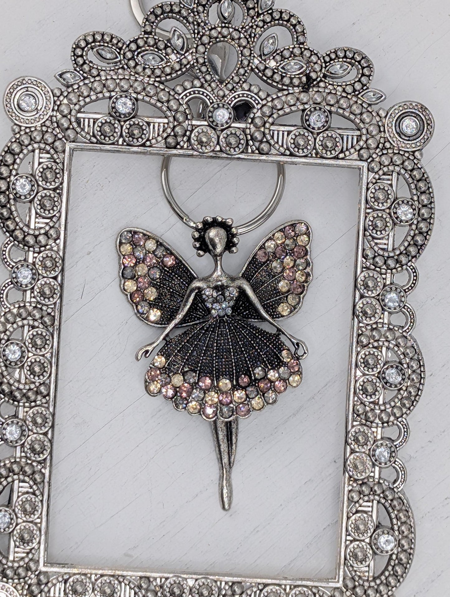 a silver-colored decorative frame with a butterfly-shaped pendant adorned with sparkling rhinestones.