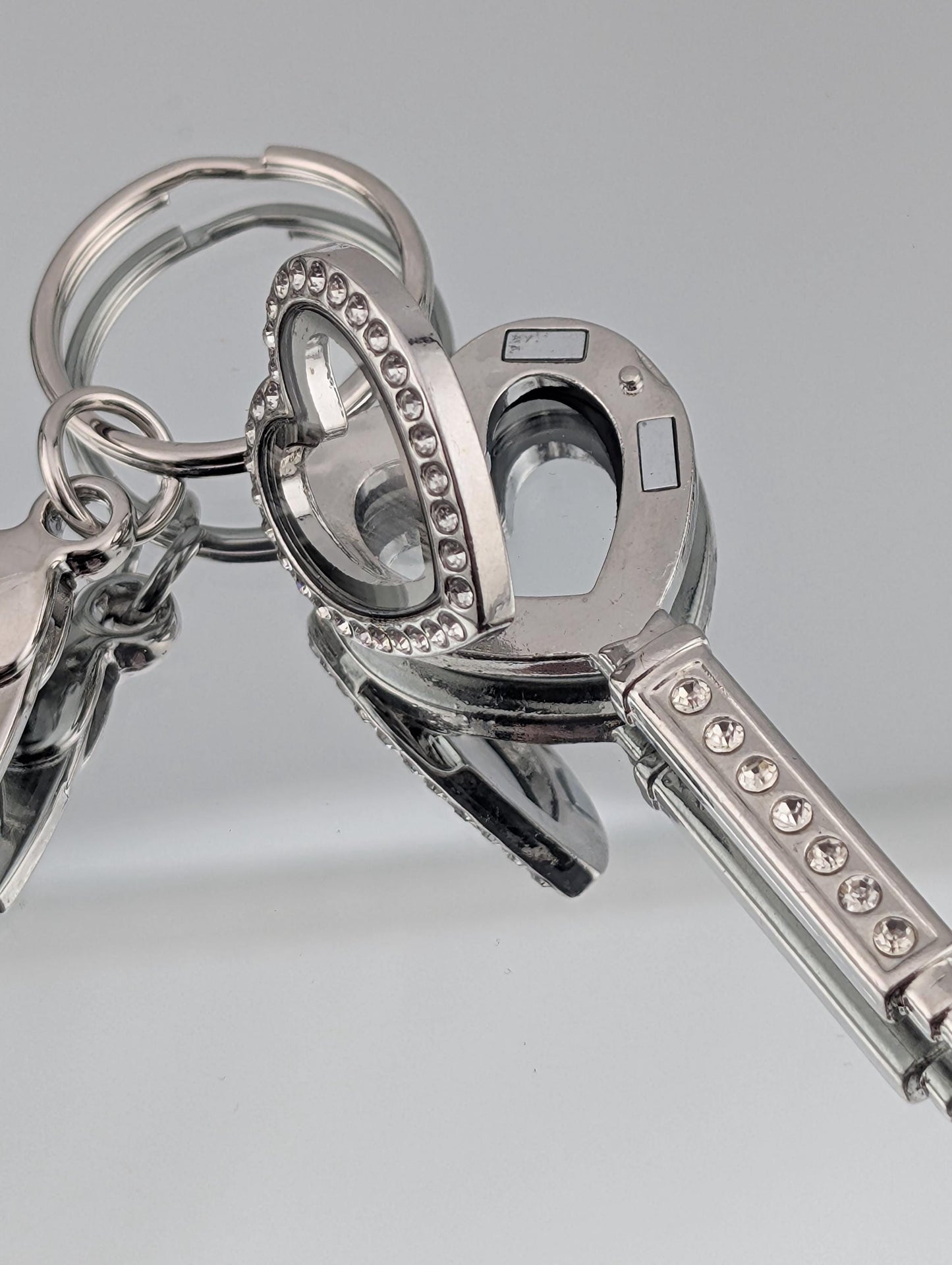 A set of silver keys with heart-shaped cutouts and rhinestones, arranged in a close-up view.