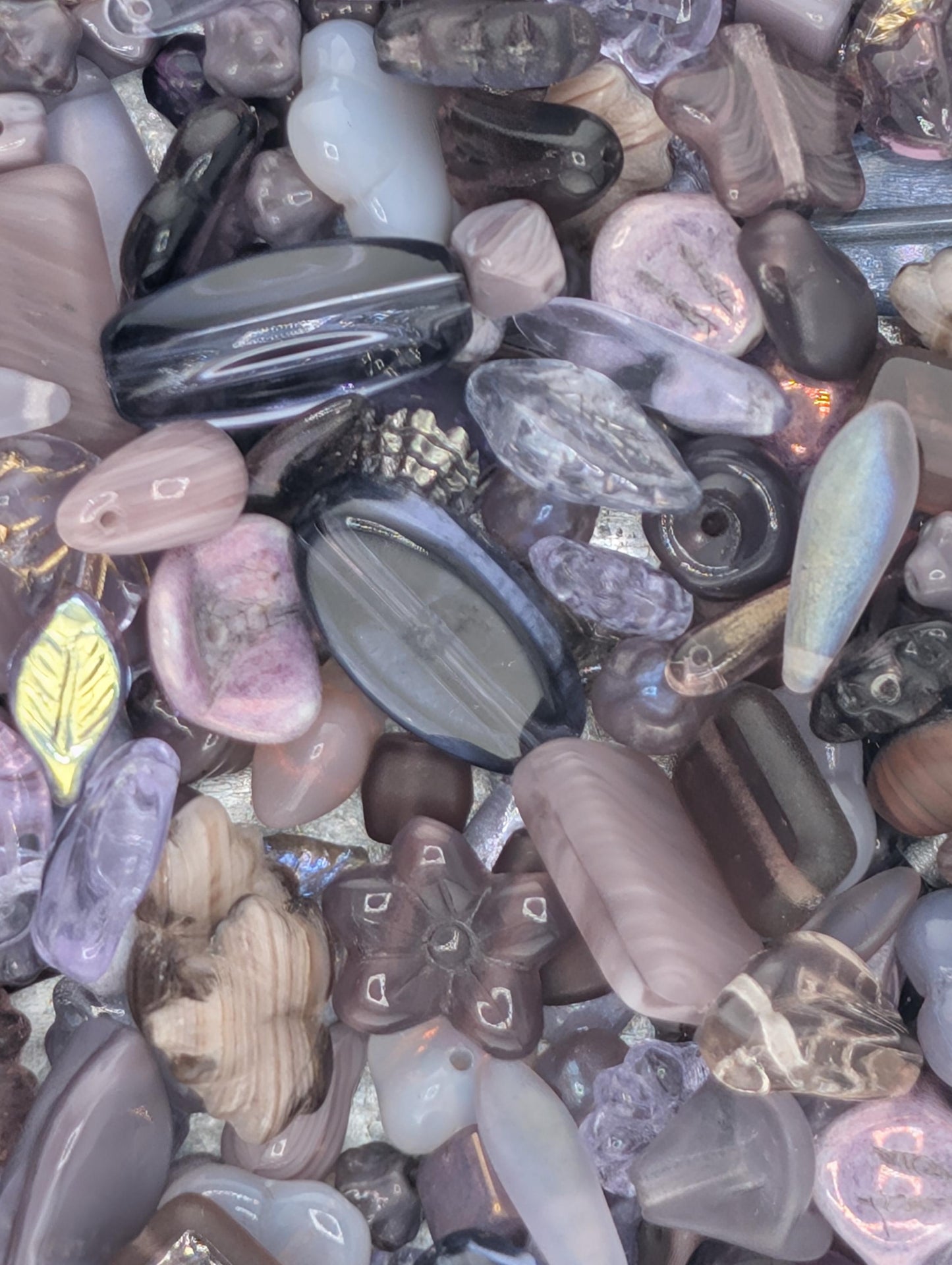 a variety of colorful glass beads and stones, including clear, purple, and brown hues, arranged in a visually appealing manner.