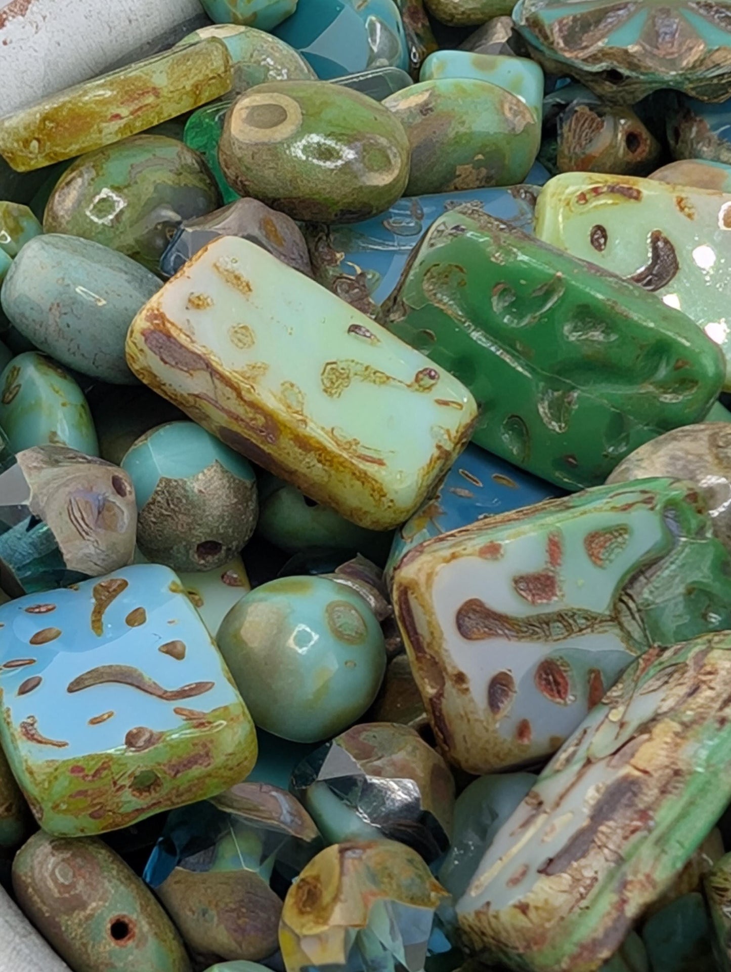 a collection of various colorful beads and stones, including green, blue, and yellow ones, arranged together.