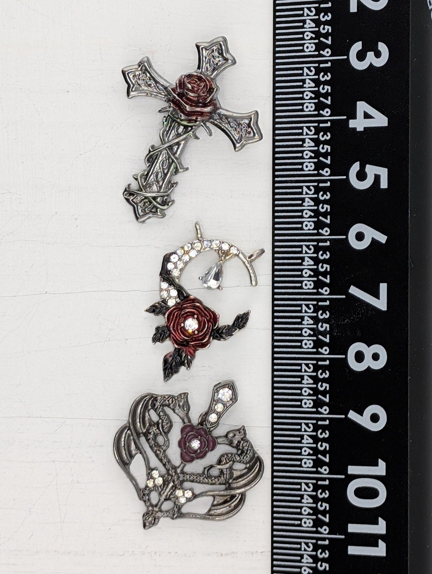 three ornate metal brooches with floral designs and rhinestones, each varying in size.