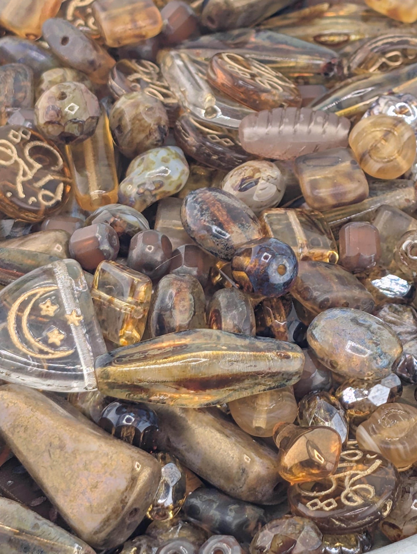 The image is a close-up view of a pile of various colored glass beads, including clear, brown, and multicolored pieces.