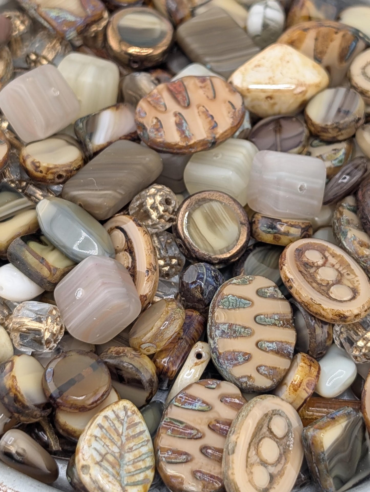 The image is a close-up of a collection of various beads and stones, including glass beads and stones in different shapes, sizes, and colors.