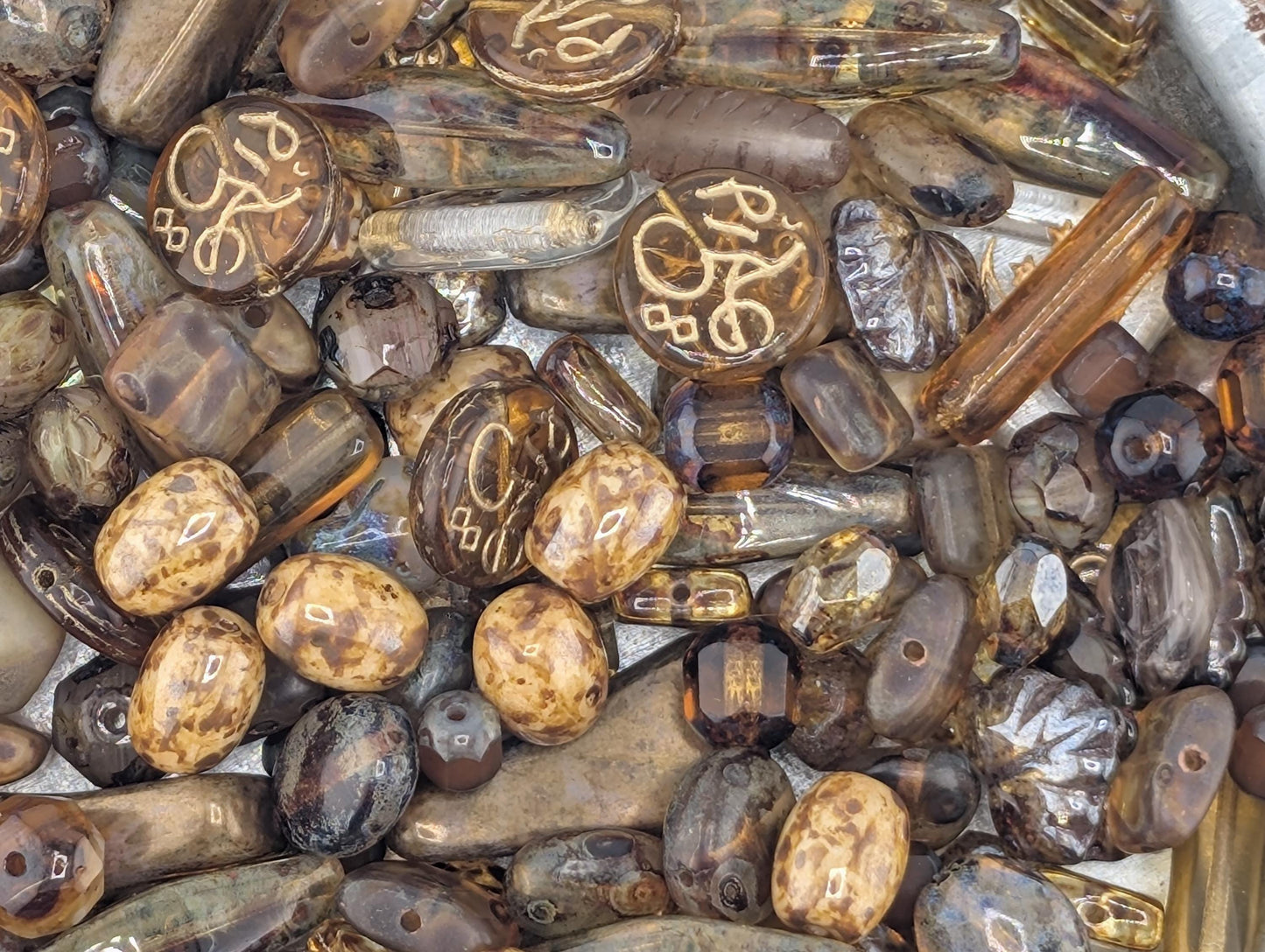 a variety of beads and stones in different shapes, sizes, and colors, including brown, black, and gold.