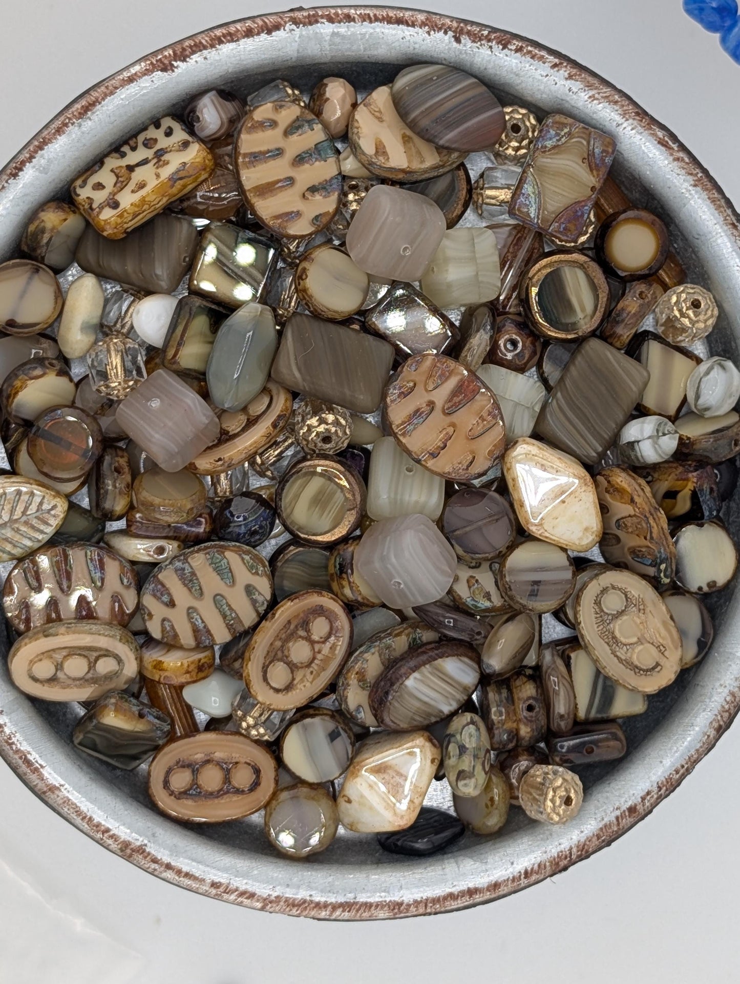 A bowl filled with various beads and stones of different shapes, sizes, and colors.