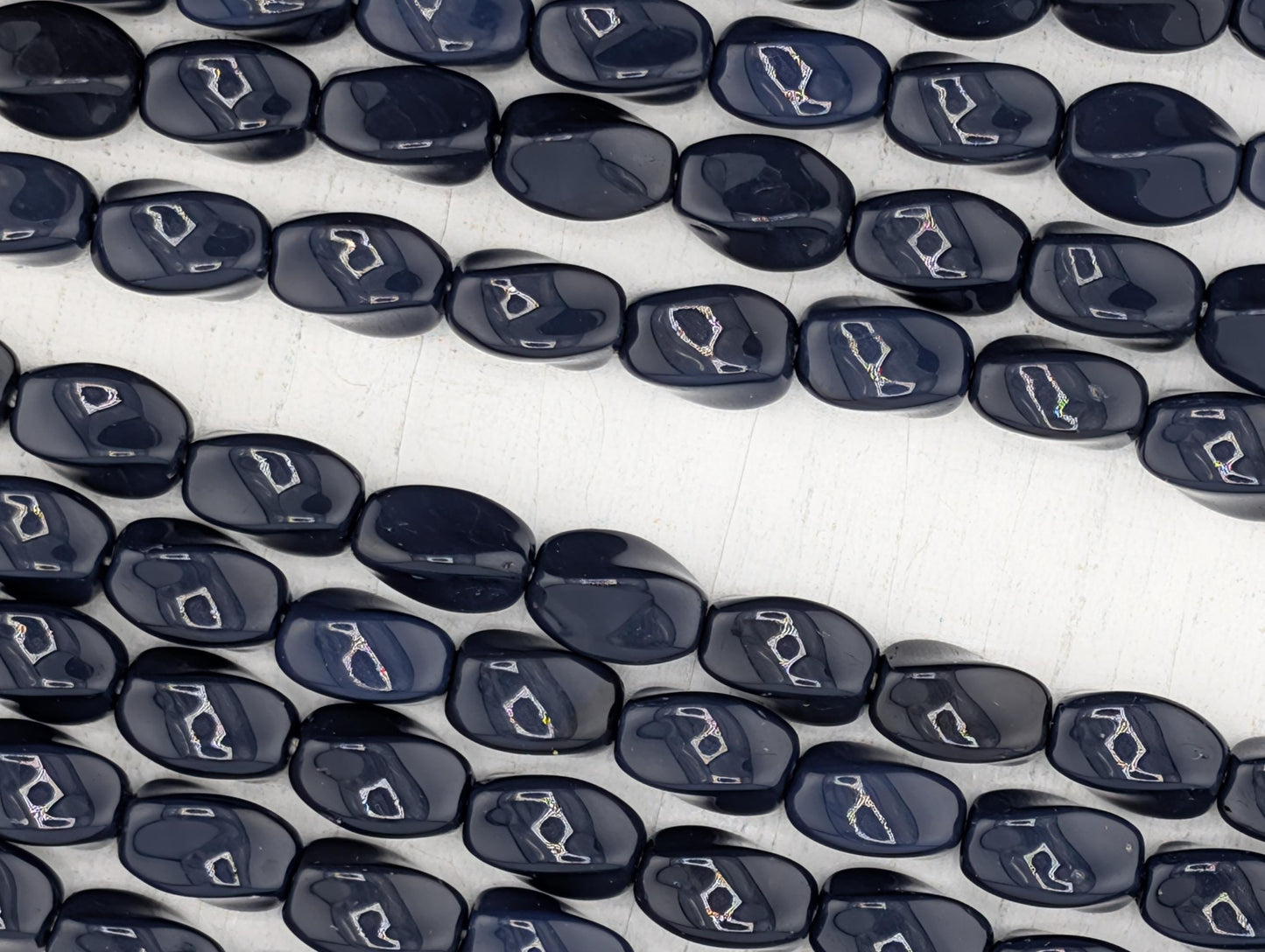 a close-up view of numerous dark blue beads arranged in a pattern, with some of the beads overlapping each other.