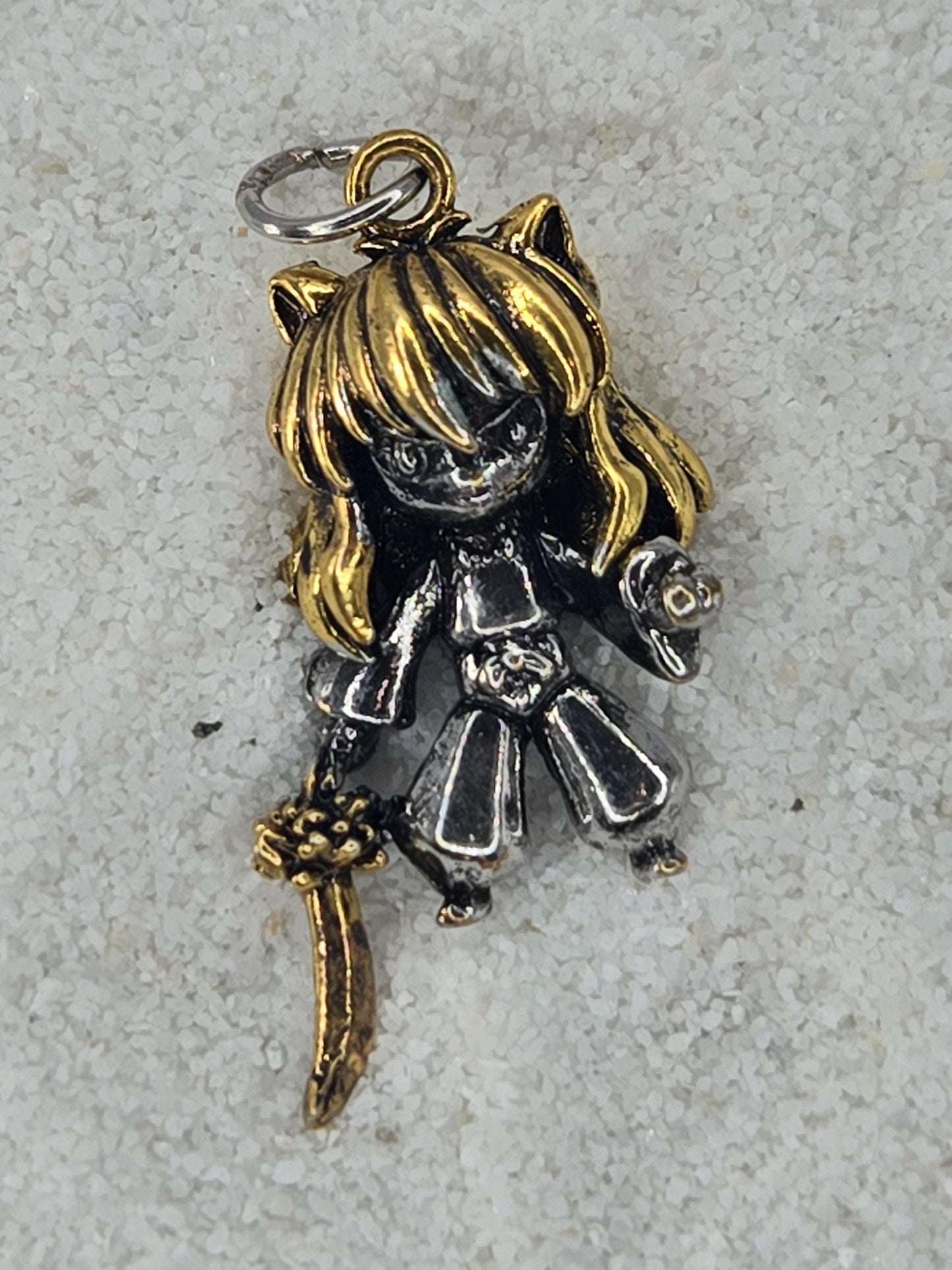 A small, metallic charm in the shape of a girl with blonde hair and a sword.