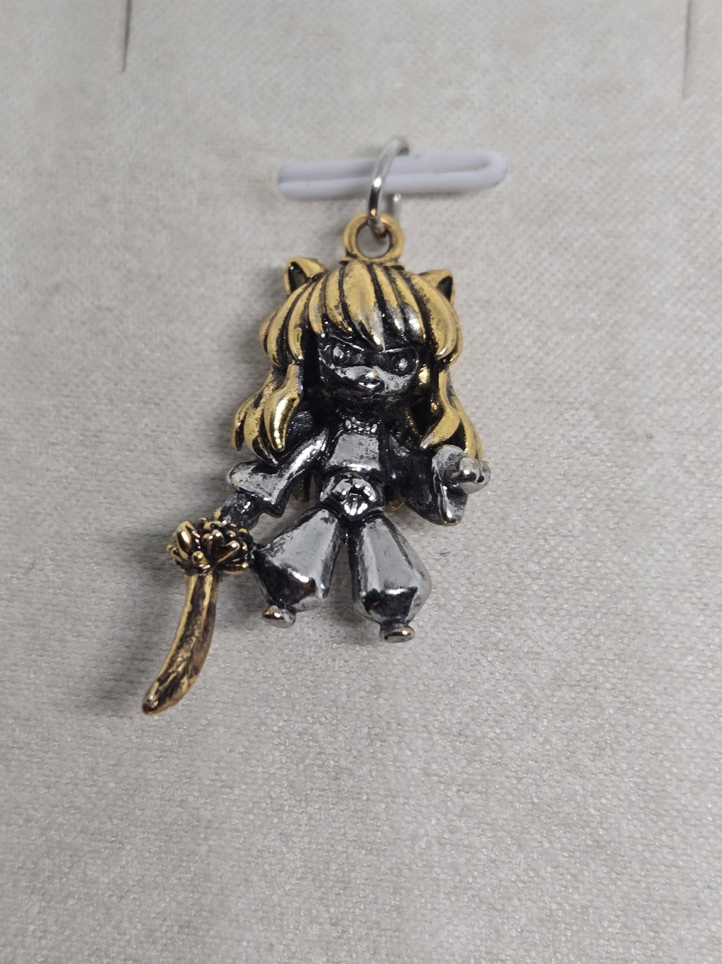 A decorative charm in the shape of a girl with a sword.