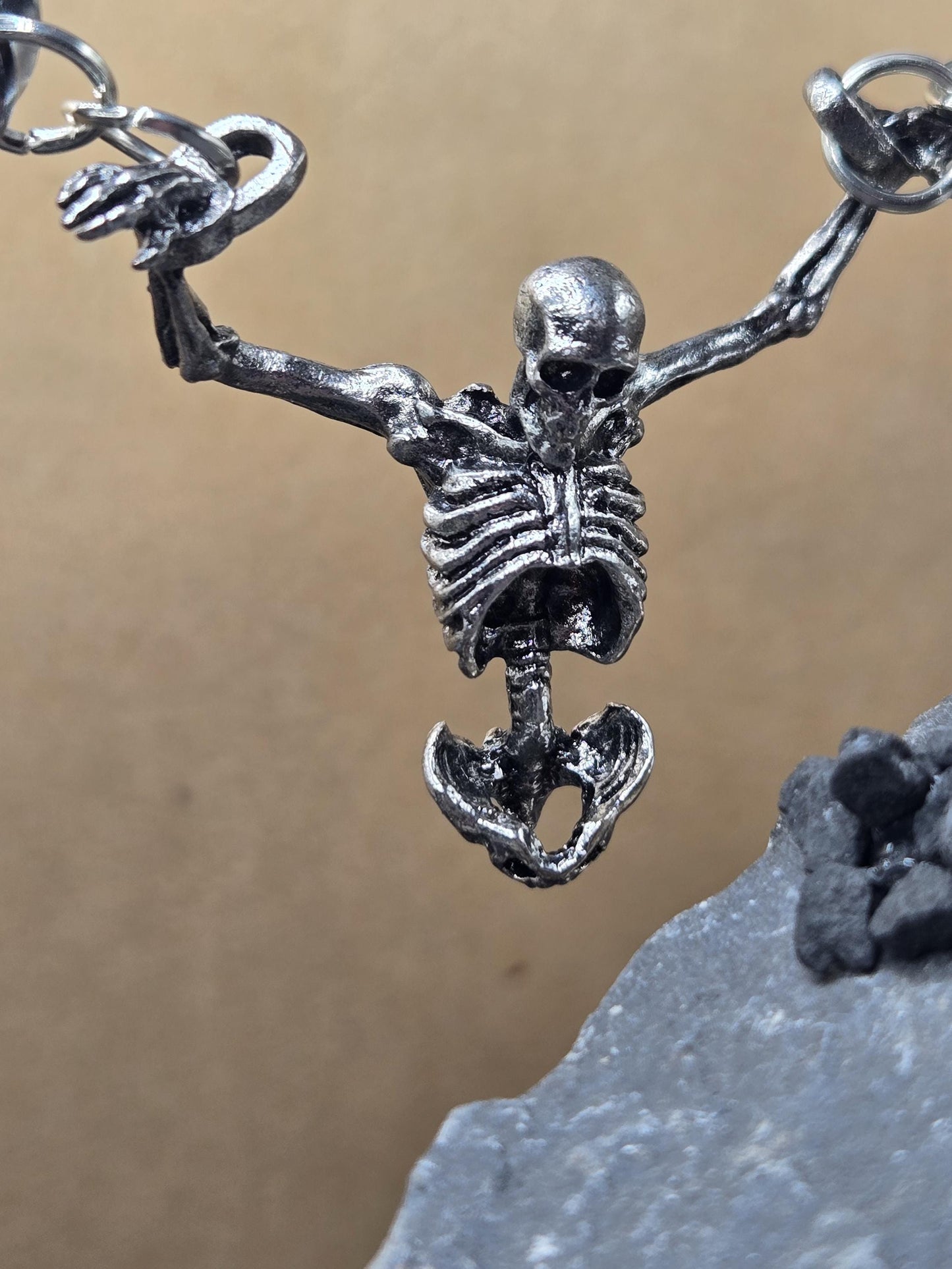 A close-up view of a metal skeleton figure hanging from a chain.