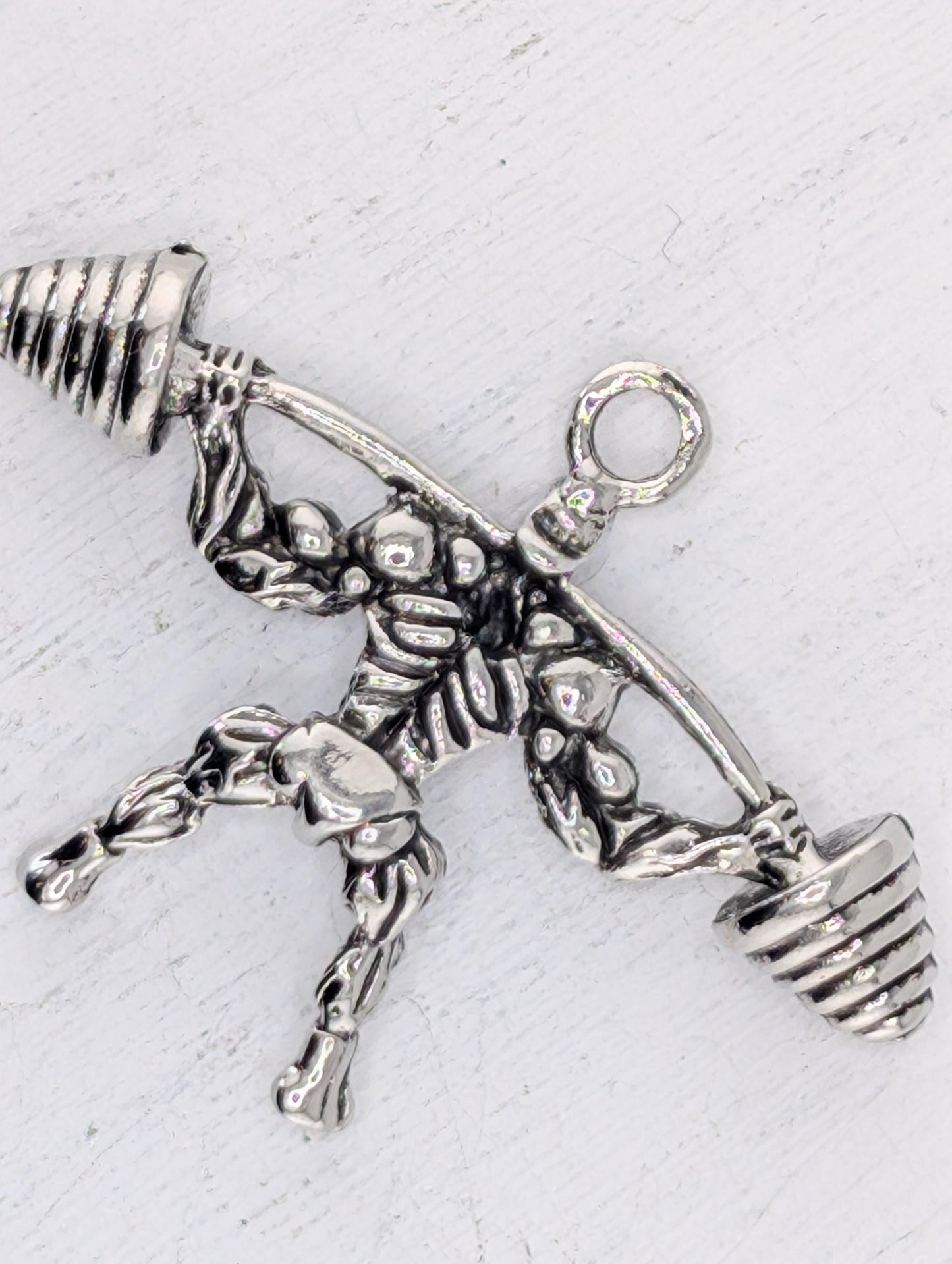 A silver-colored metal charm in the shape of a weightlifter, with a barbell and dumbbell-like weights attached to it.