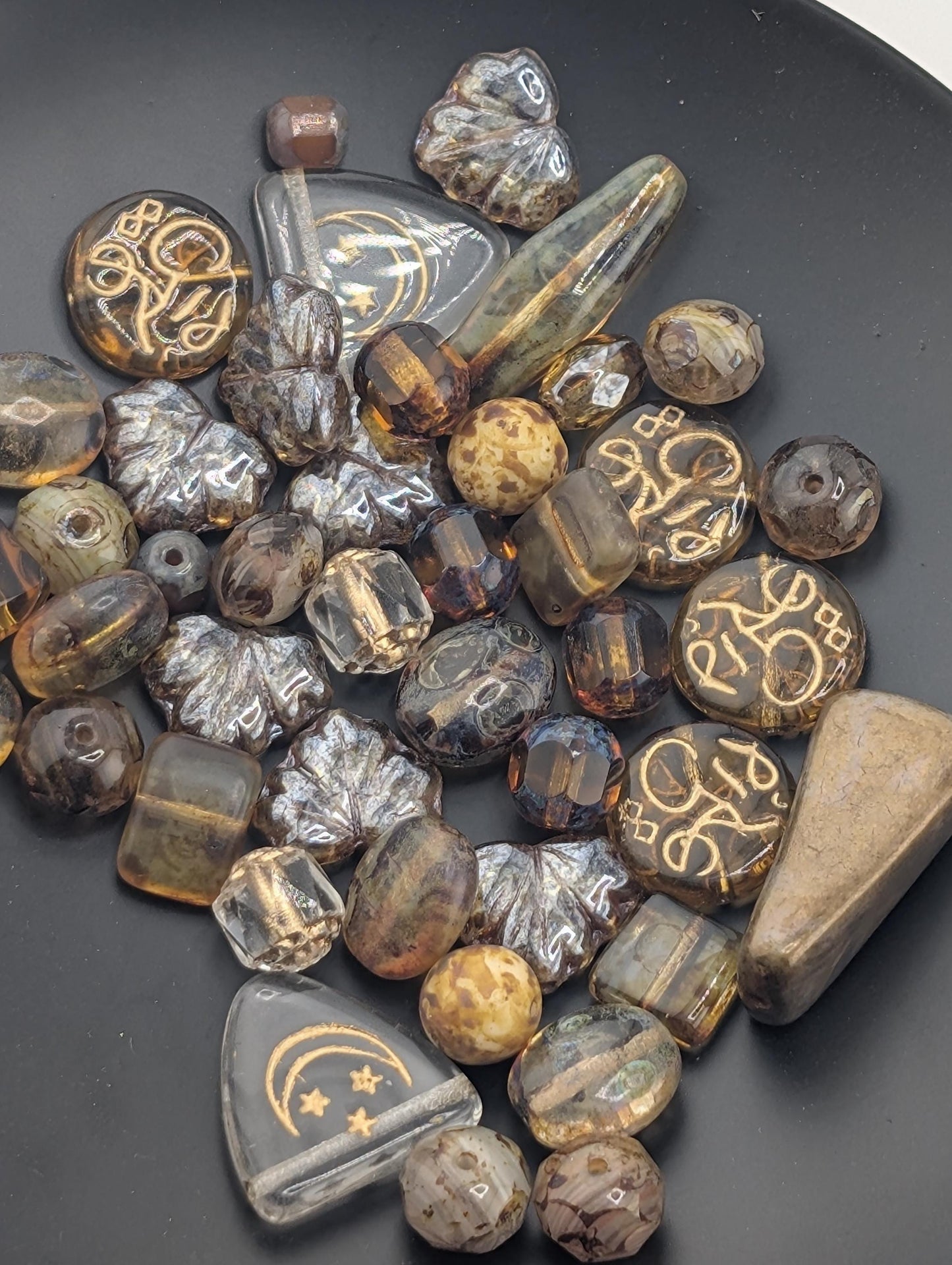 a collection of various glass beads and beads in different shapes and sizes, scattered on a dark surface.
