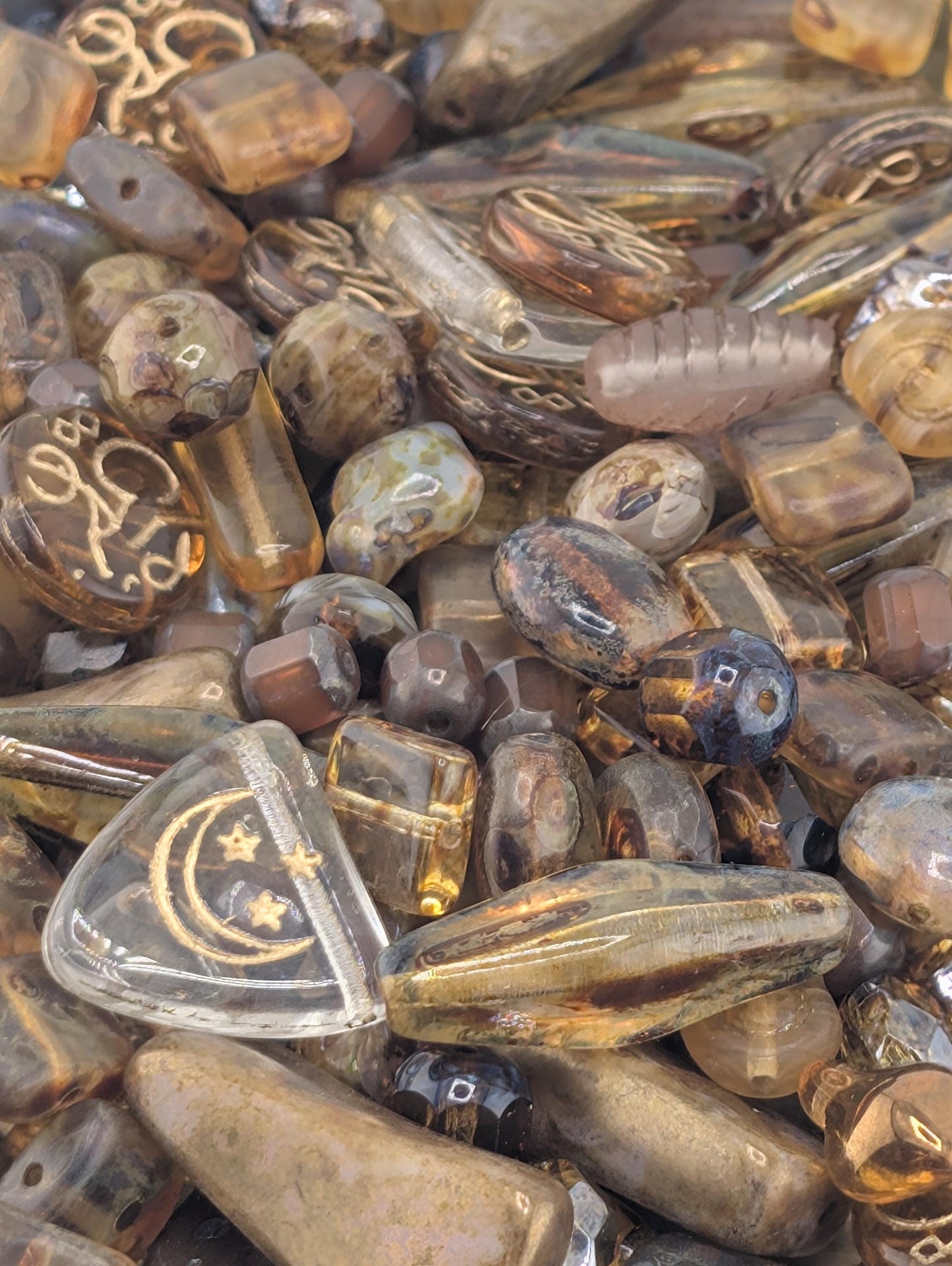 The image is a close-up of various glass beads and stones, including clear and brown glass beads, scattered together.