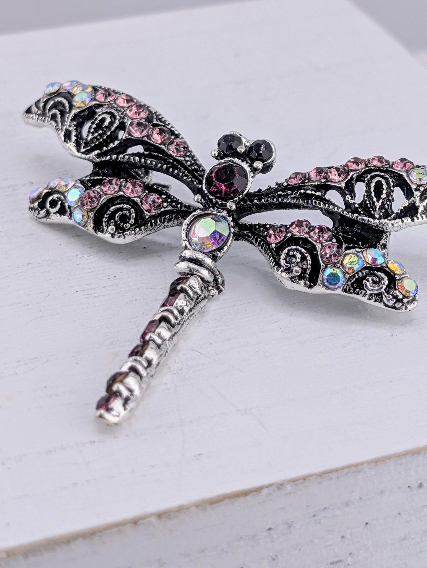 A decorative silver butterfly brooch with colorful gemstones and intricate designs.