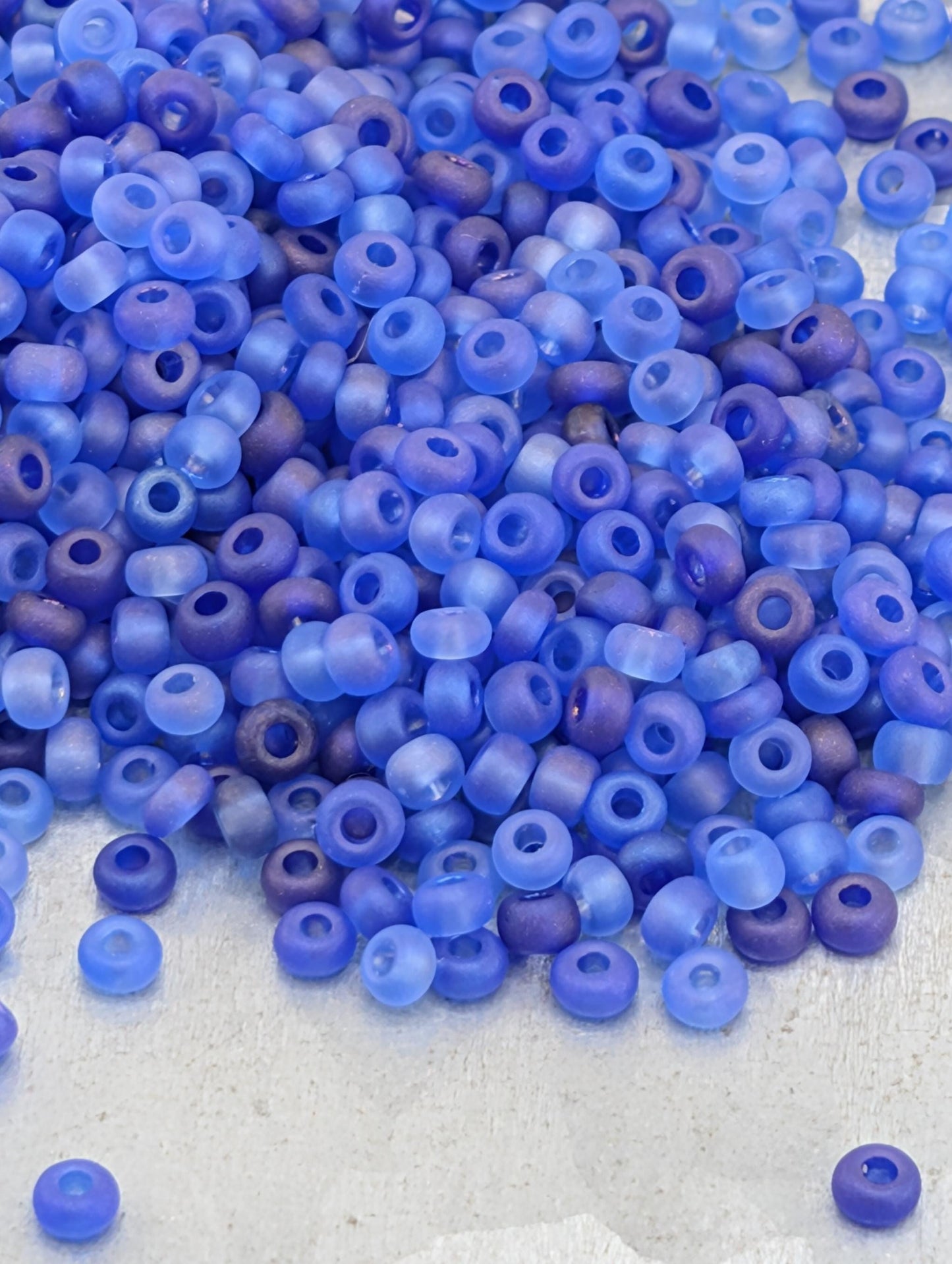 A pile of blue and purple glass beads on a white surface.