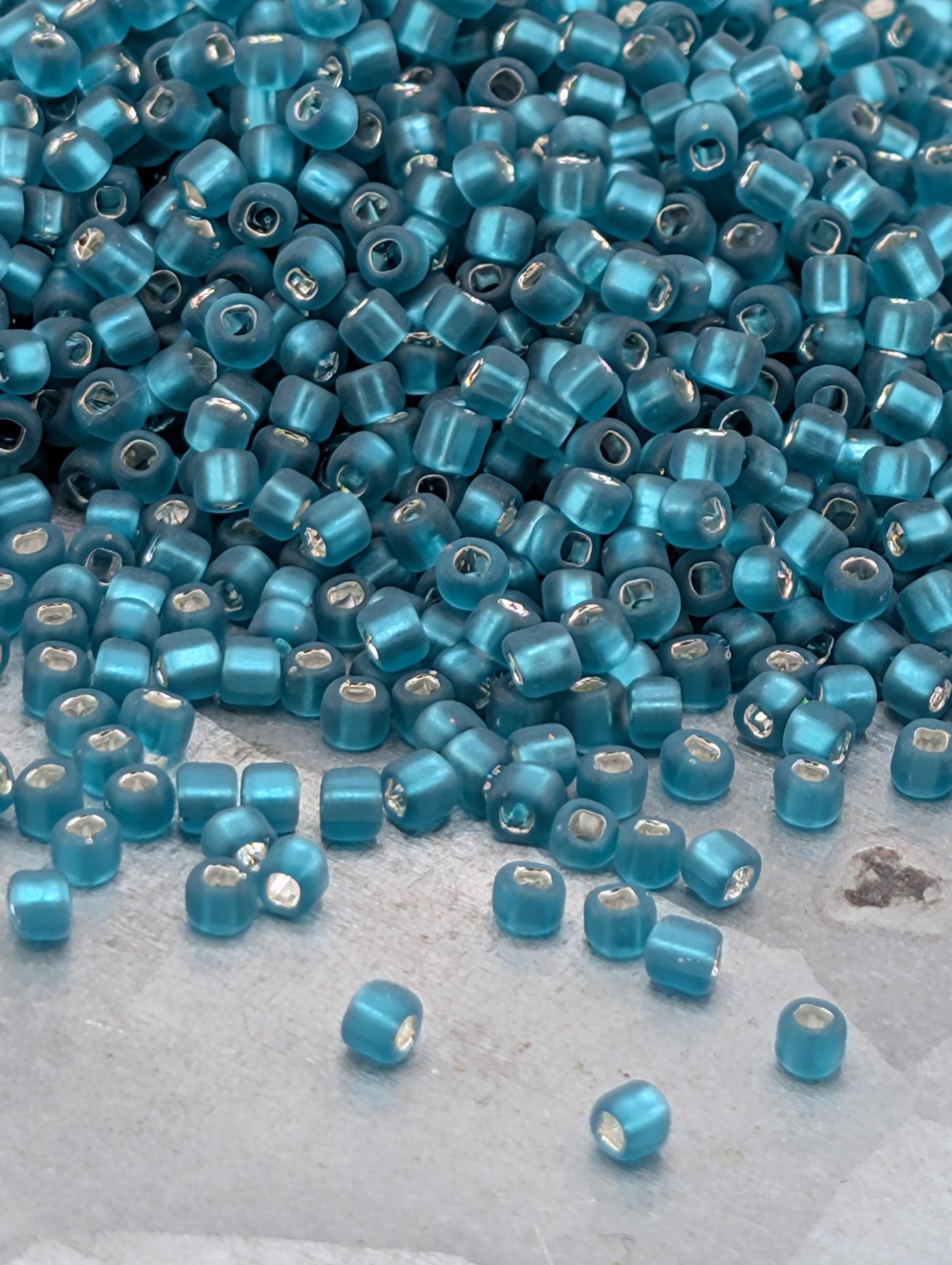 a large pile of small, blue beads scattered on a surface.
