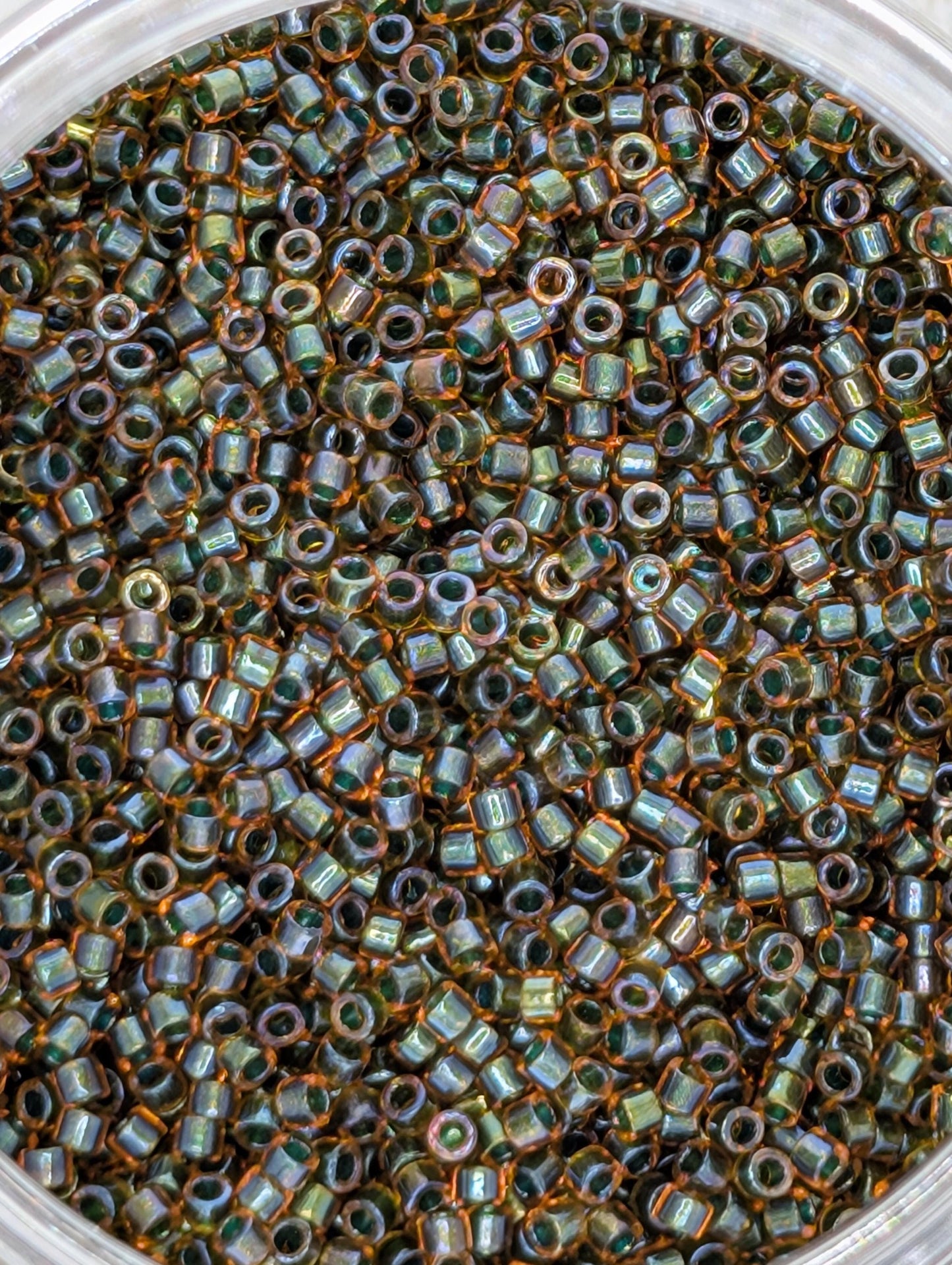 A close-up image of a large pile of small, round beads in various colors, including shades of green, orange, and brown.