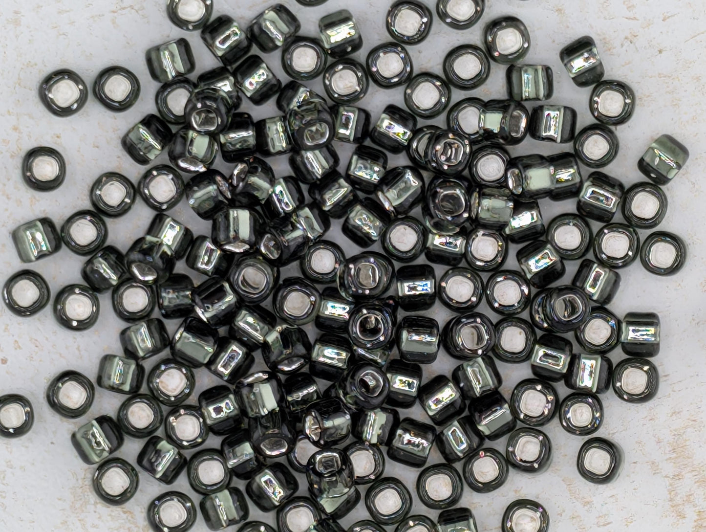 5167SB Silver Lined Translucent Gunmetal Round With Square Hole 6/0 (15g Pkg)