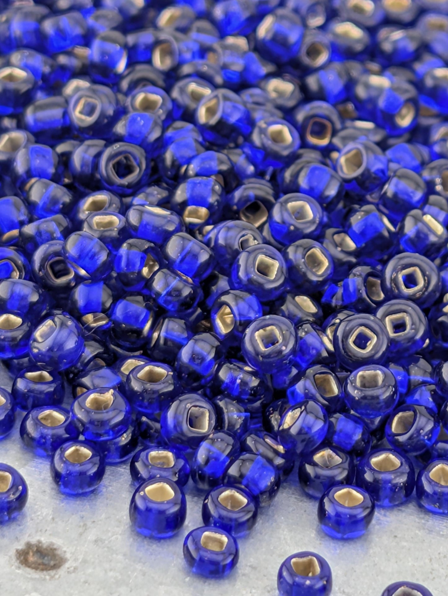 a large pile of blue glass beads with gold accents, scattered on a surface.