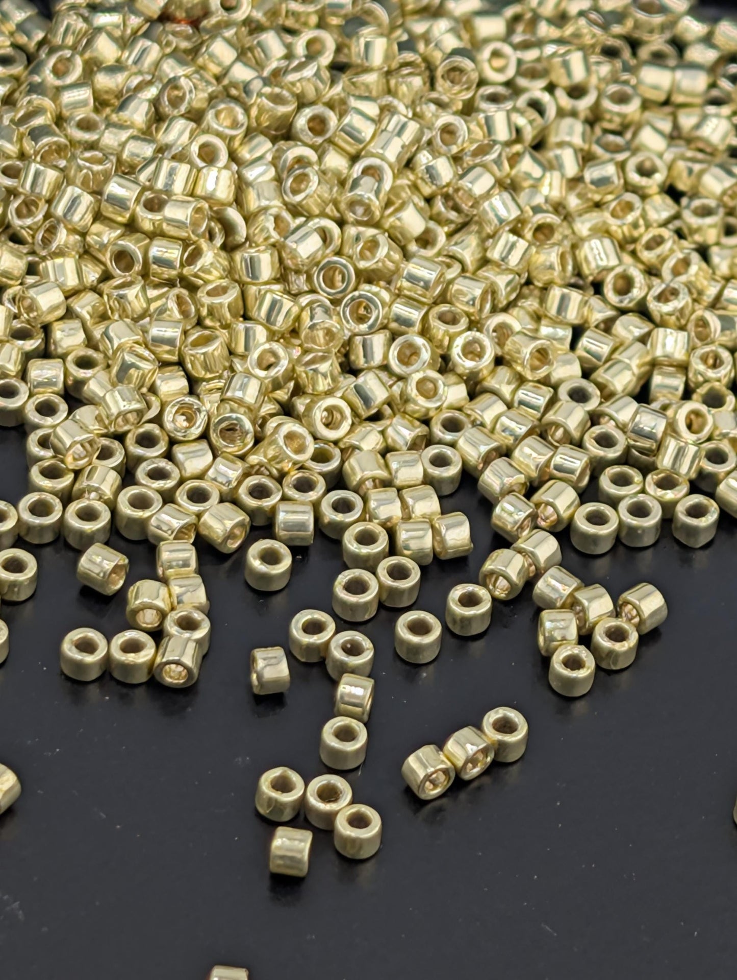 a pile of small, round, metallic beads or nuts scattered on a dark surface.