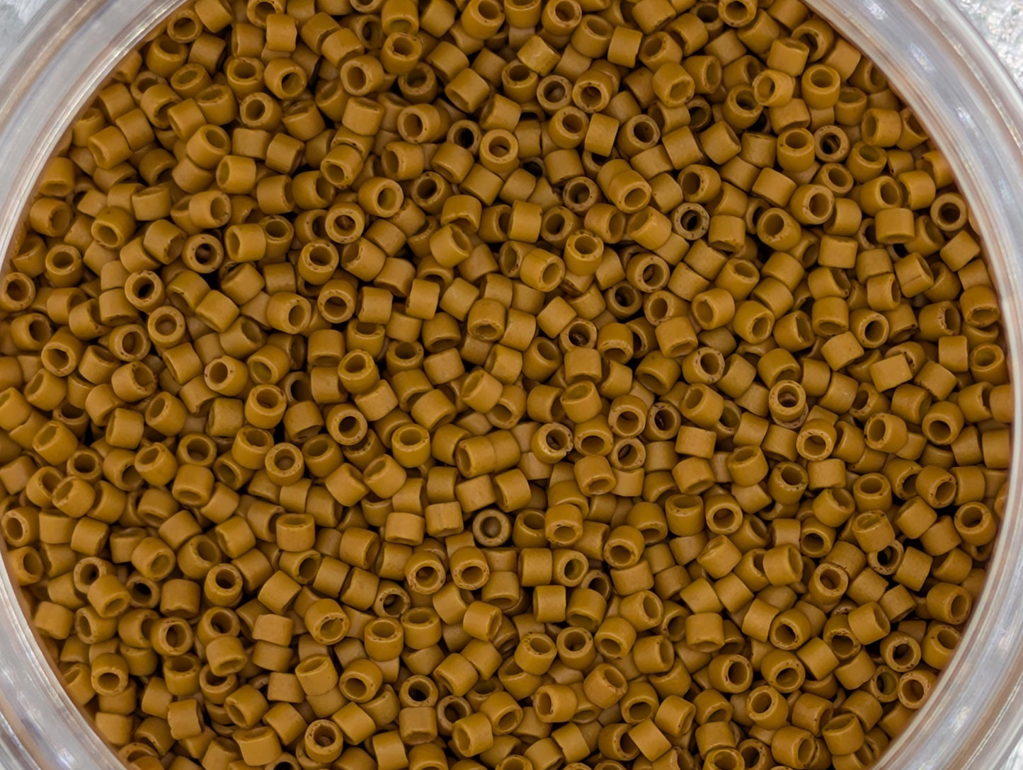 A close-up image of a container filled with small, round, brown objects, likely beads or grains, arranged in a visually appealing manner.