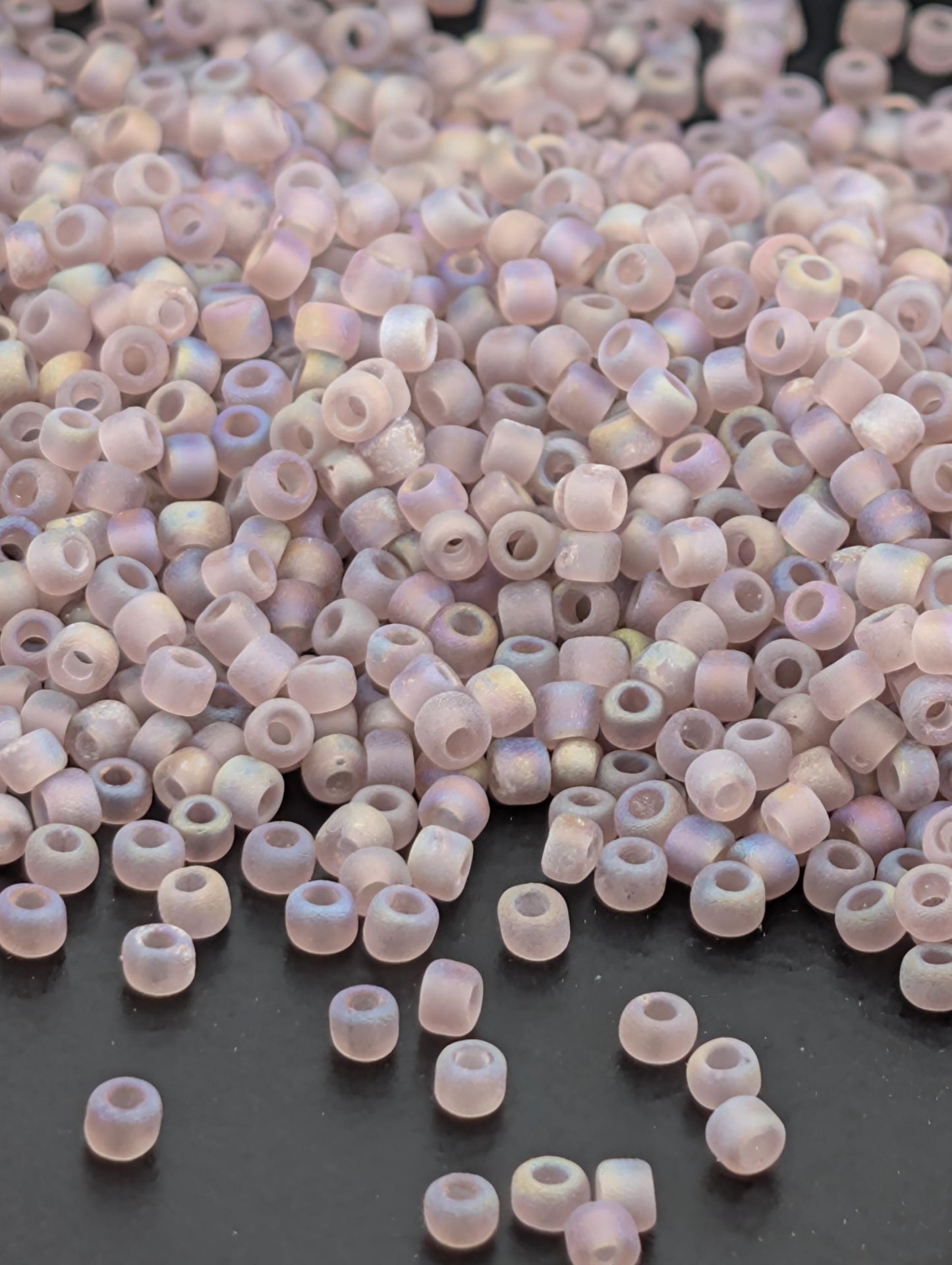 a large pile of small, round beads scattered on a dark surface.