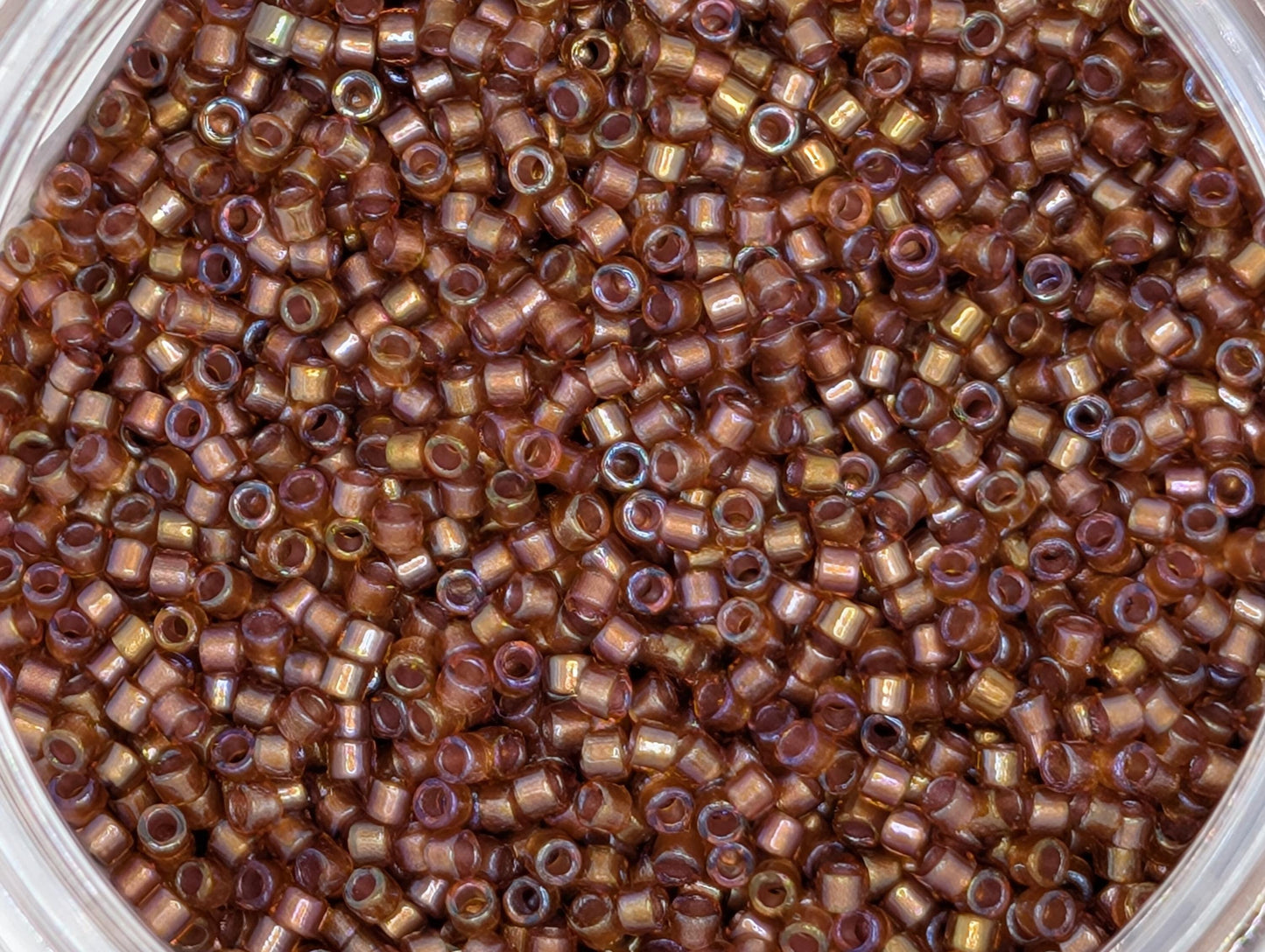 A close-up image of a large pile of small, round beads in various shades of brown.