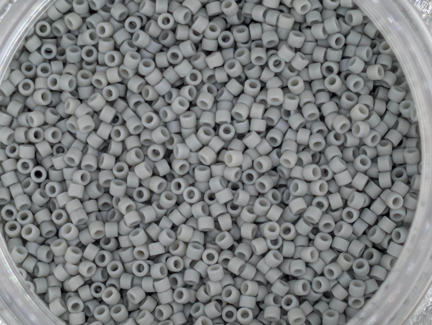 A close-up image of a container filled with small, white beads or plastic beads.
