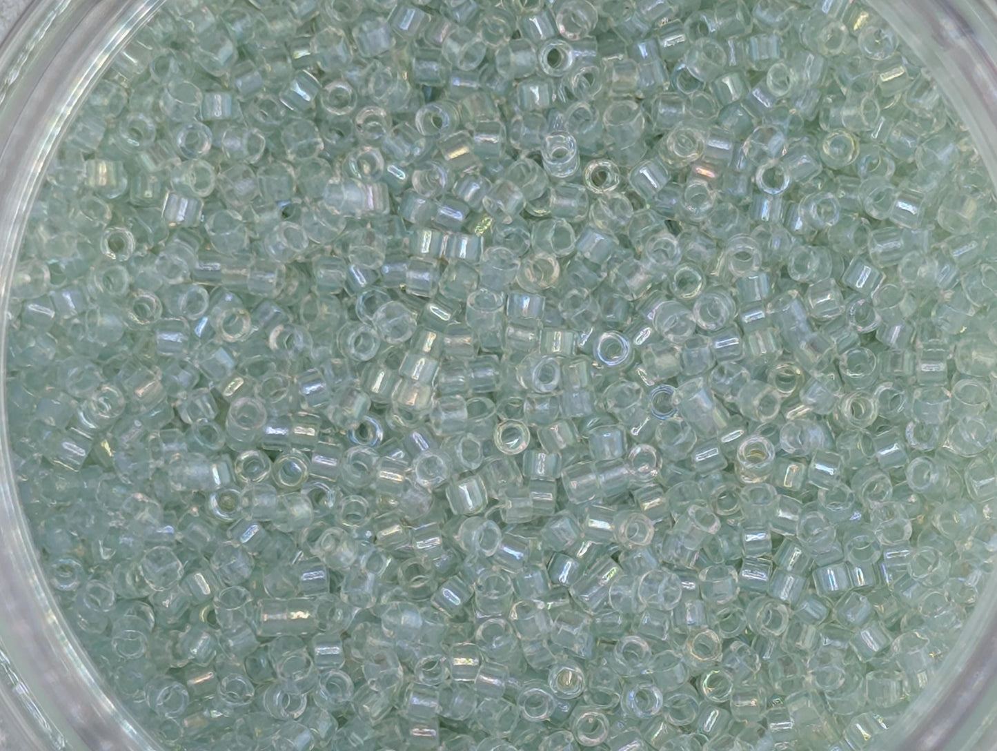 A close-up image of a transparent material, possibly glass or plastic, filled with small, clear beads or grains.