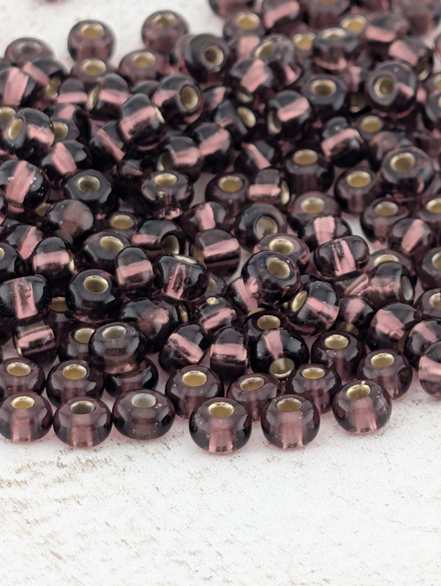 a large pile of purple and black beads scattered on a white surface.