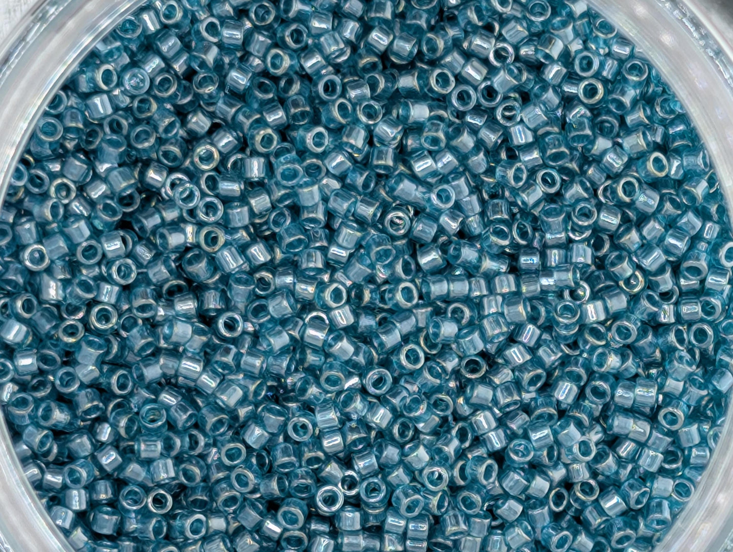 A close-up image of a glass jar filled with numerous small blue beads or beads, creating a visually striking and colorful pattern.