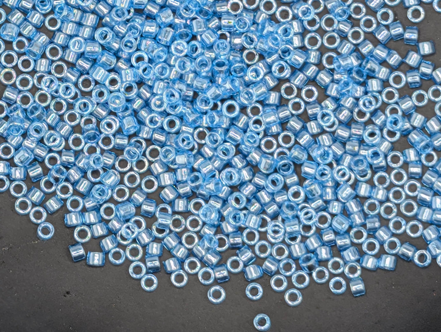 a large number of small, round blue beads scattered across a dark surface.