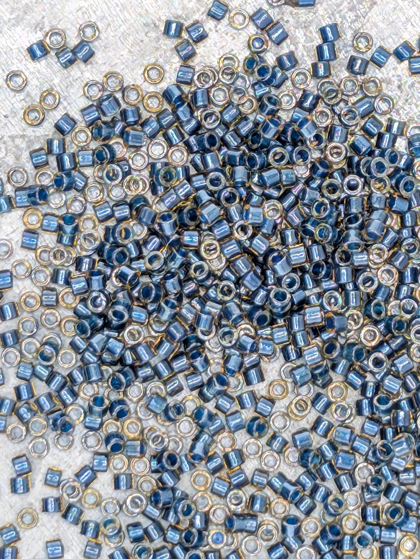 The image is a close-up of numerous small blue and gold beads scattered across a surface.