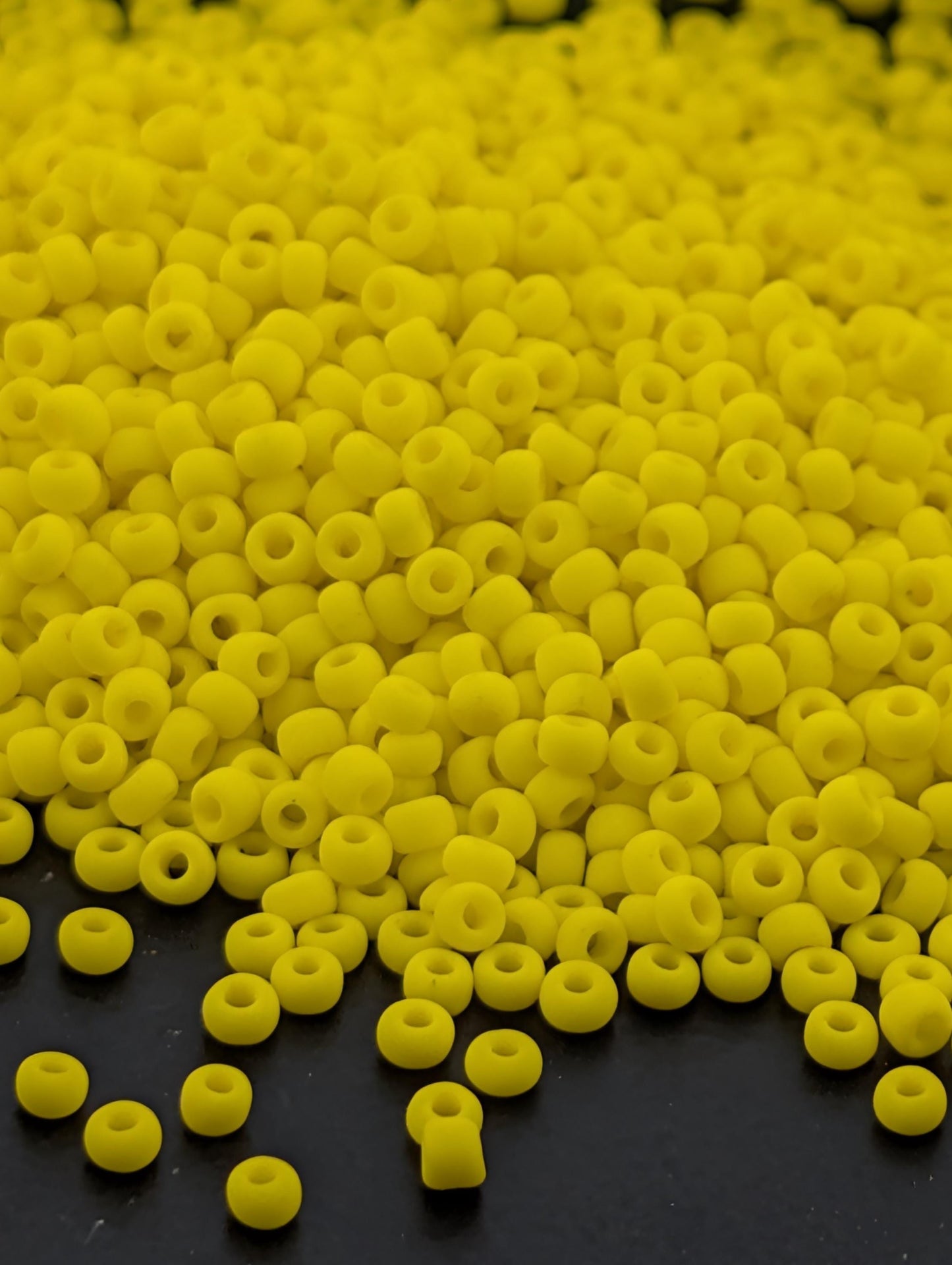 A large pile of yellow beads or beads scattered on a dark surface.
