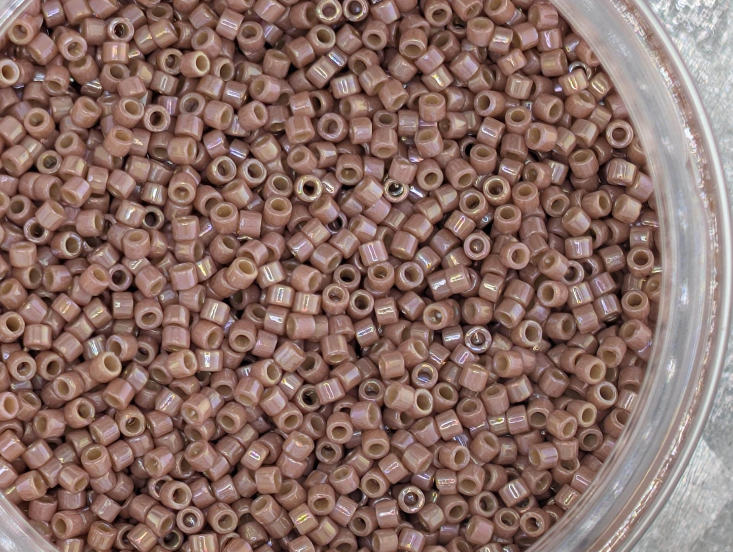 A close-up image of a container filled with numerous small, round beads in a light brown color.