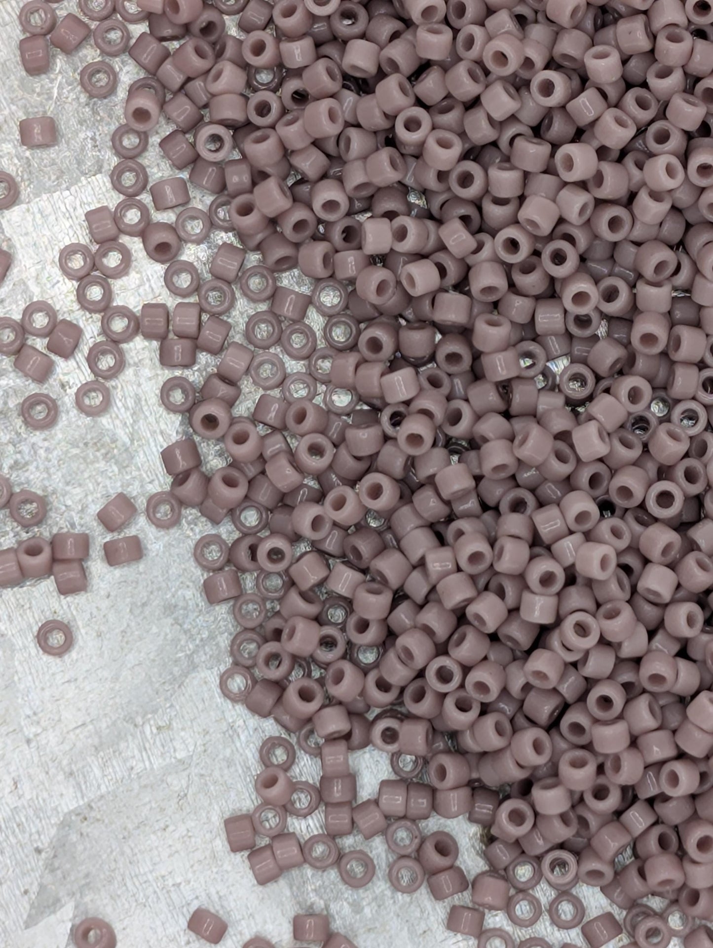 a large pile of small, round beads in various shades of pink, scattered across a surface.