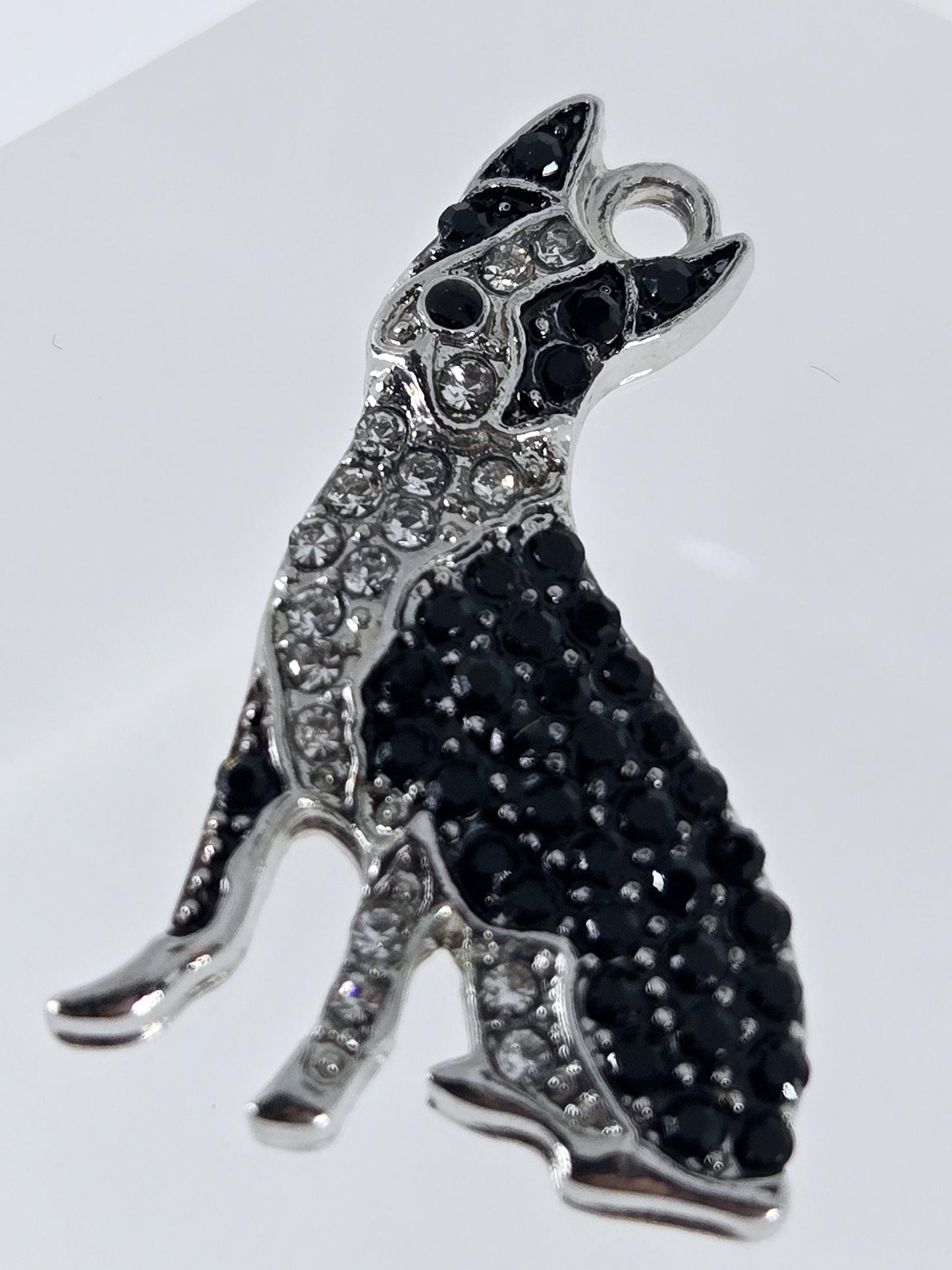A silver and black charm in the shape of a dog, adorned with numerous small black diamonds.