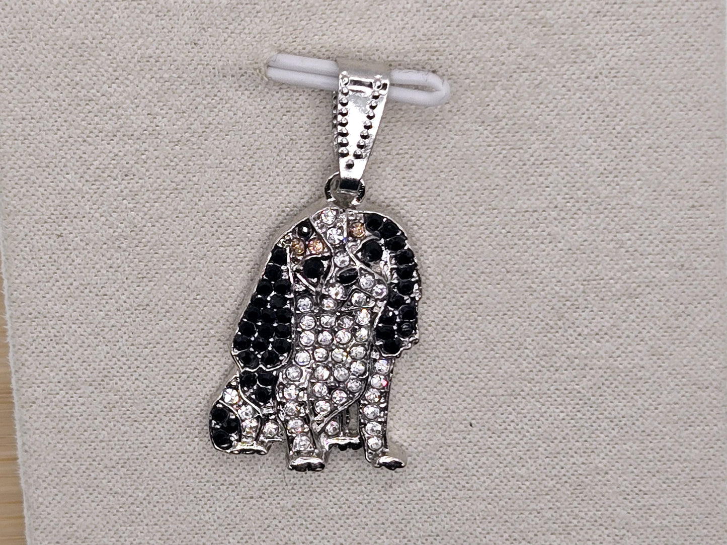 A silver-toned pendant in the shape of a dog, adorned with numerous small diamonds.