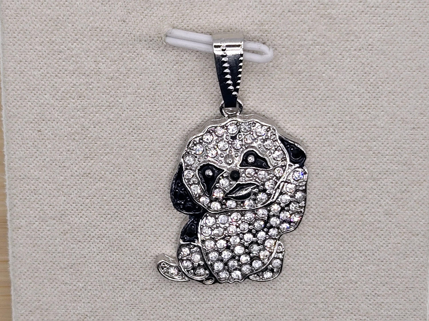 A silver pendant in the shape of a dog, adorned with numerous sparkling diamonds.