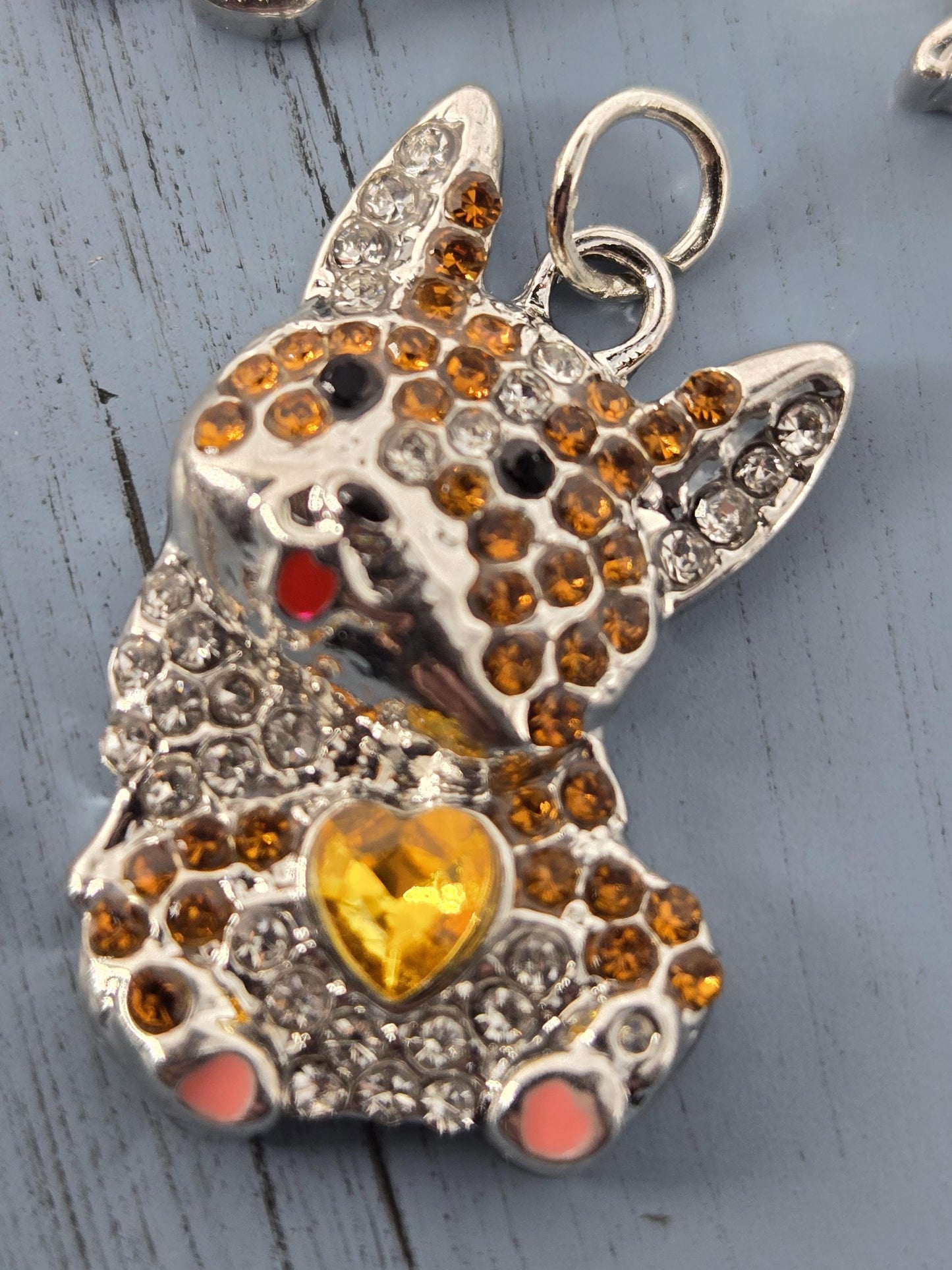 A close-up image of a decorative pendant featuring a detailed design with a heart-shaped gemstone and sparkling rhinestones.