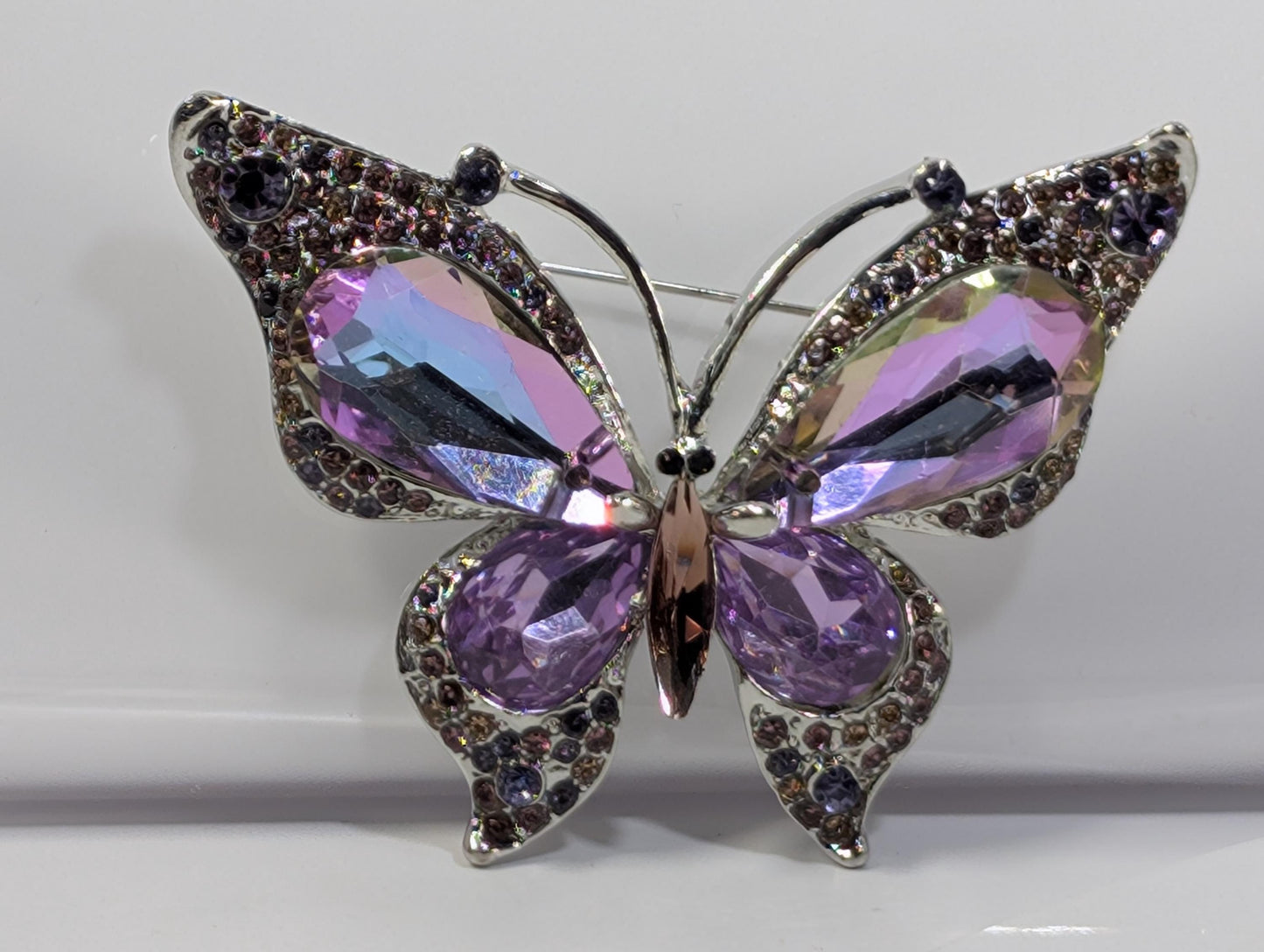 A silver butterfly brooch adorned with purple gemstones.
