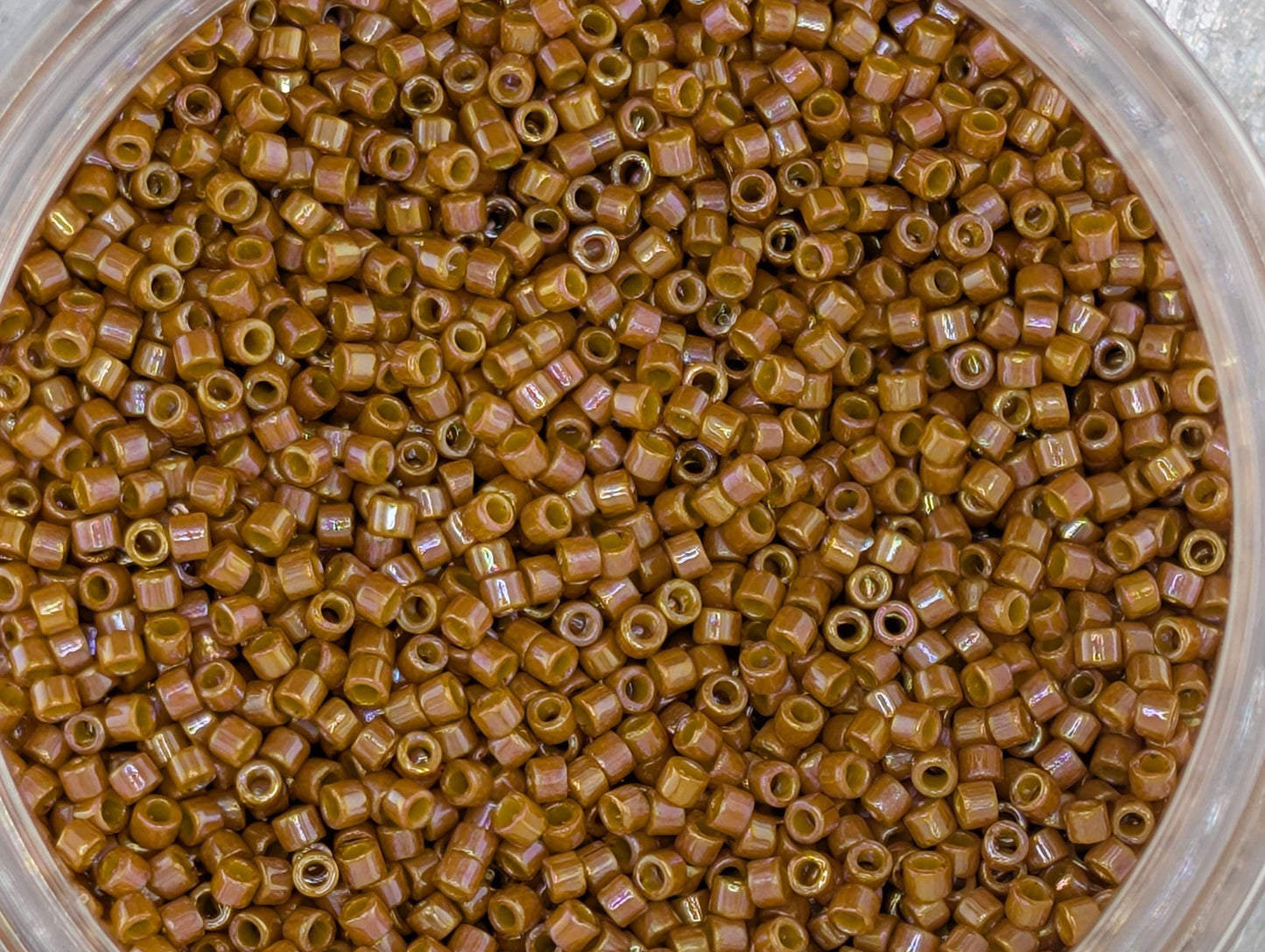 A close-up image of a container filled with numerous small, brown beads or grains.