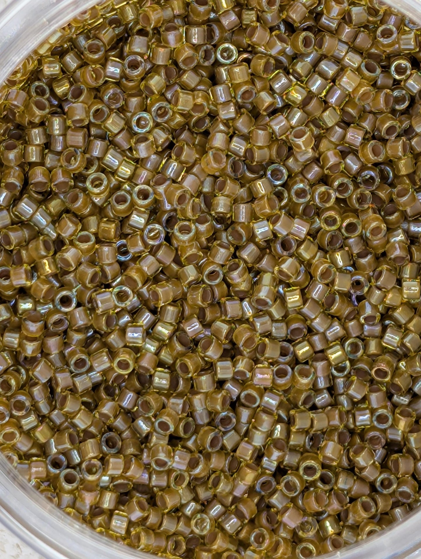 A close-up image of a container filled with numerous small, round beads in various shades of brown.