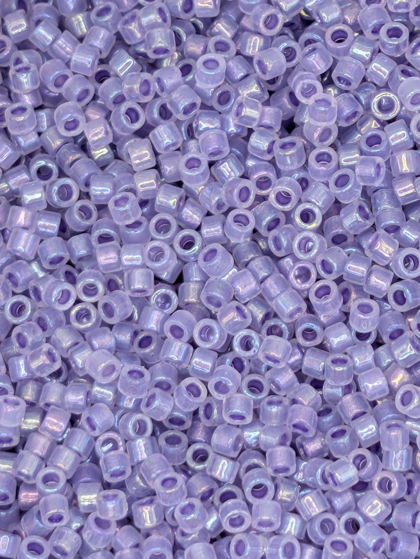 The image is a close-up of numerous small, clear beads in various shades of purple.