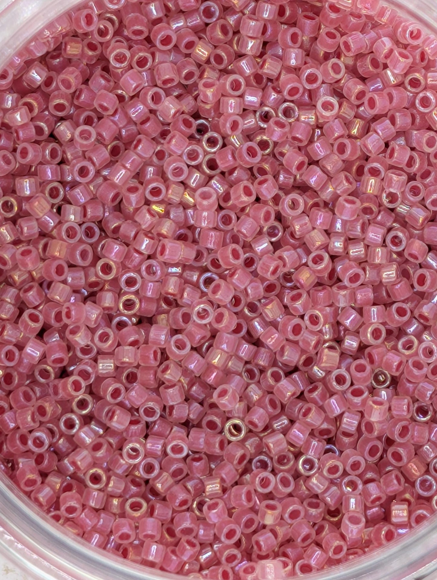 A close-up image of a container filled with numerous small, pink beads.