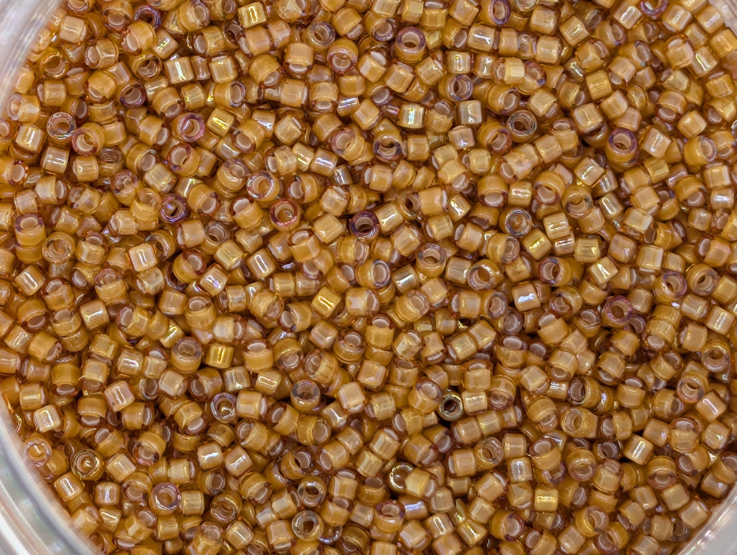 A close-up image of a container filled with numerous small, round, yellow beads.