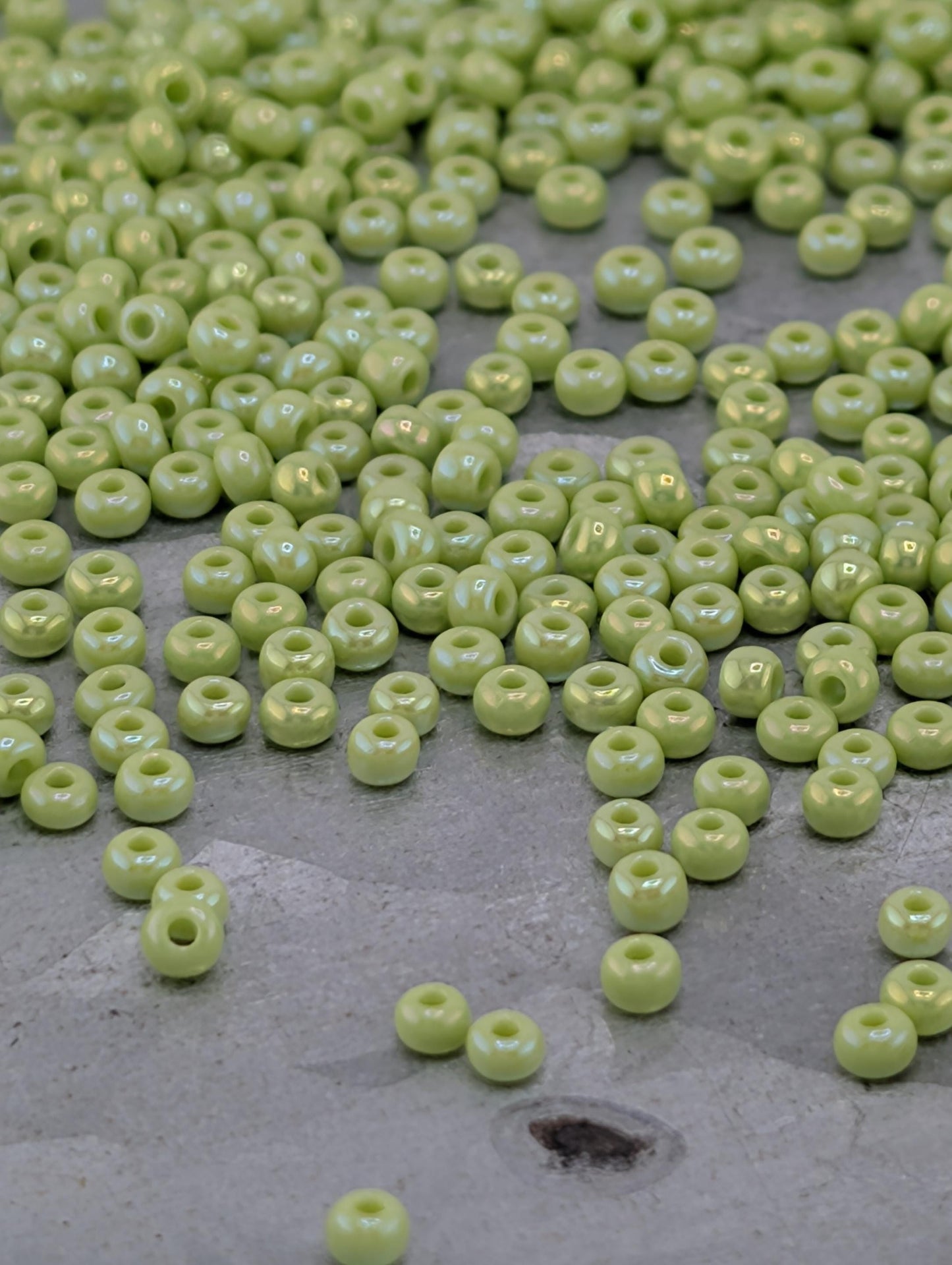 a collection of small, round, green beads scattered on a gray surface.